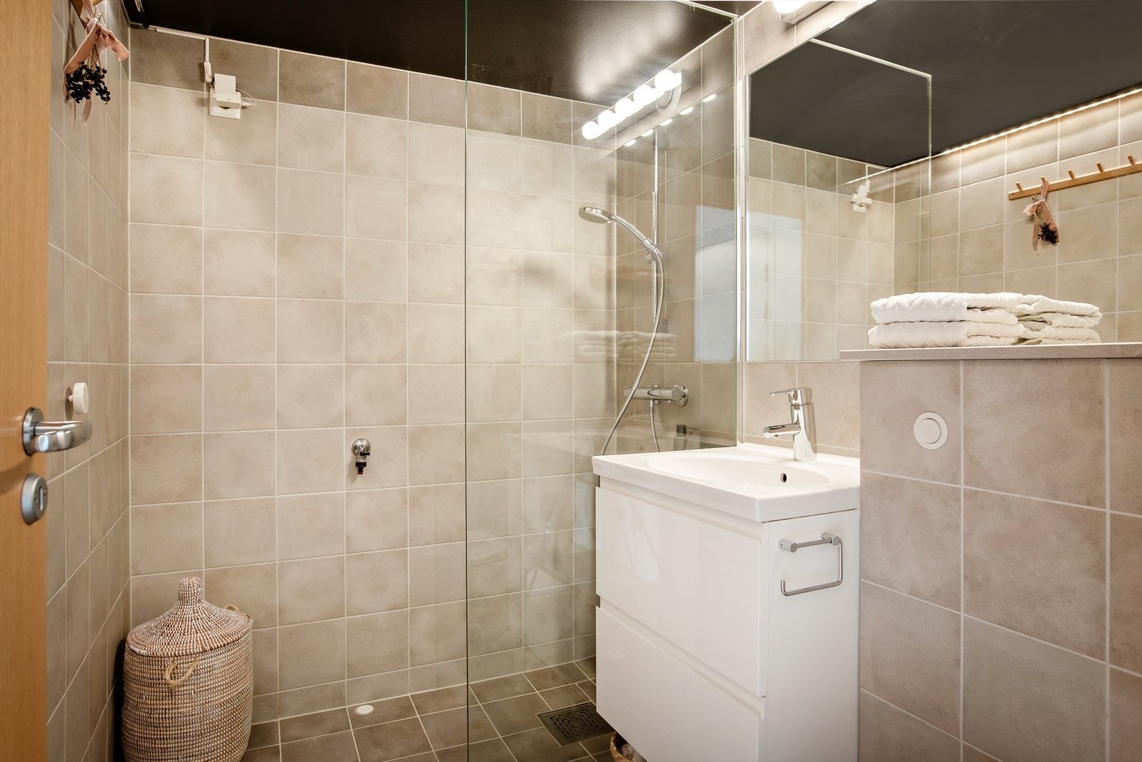 Badet er innredet med vegghengt toalett, baderomsinnredning og dusjhjørne med fast glassvegg Galleribilde