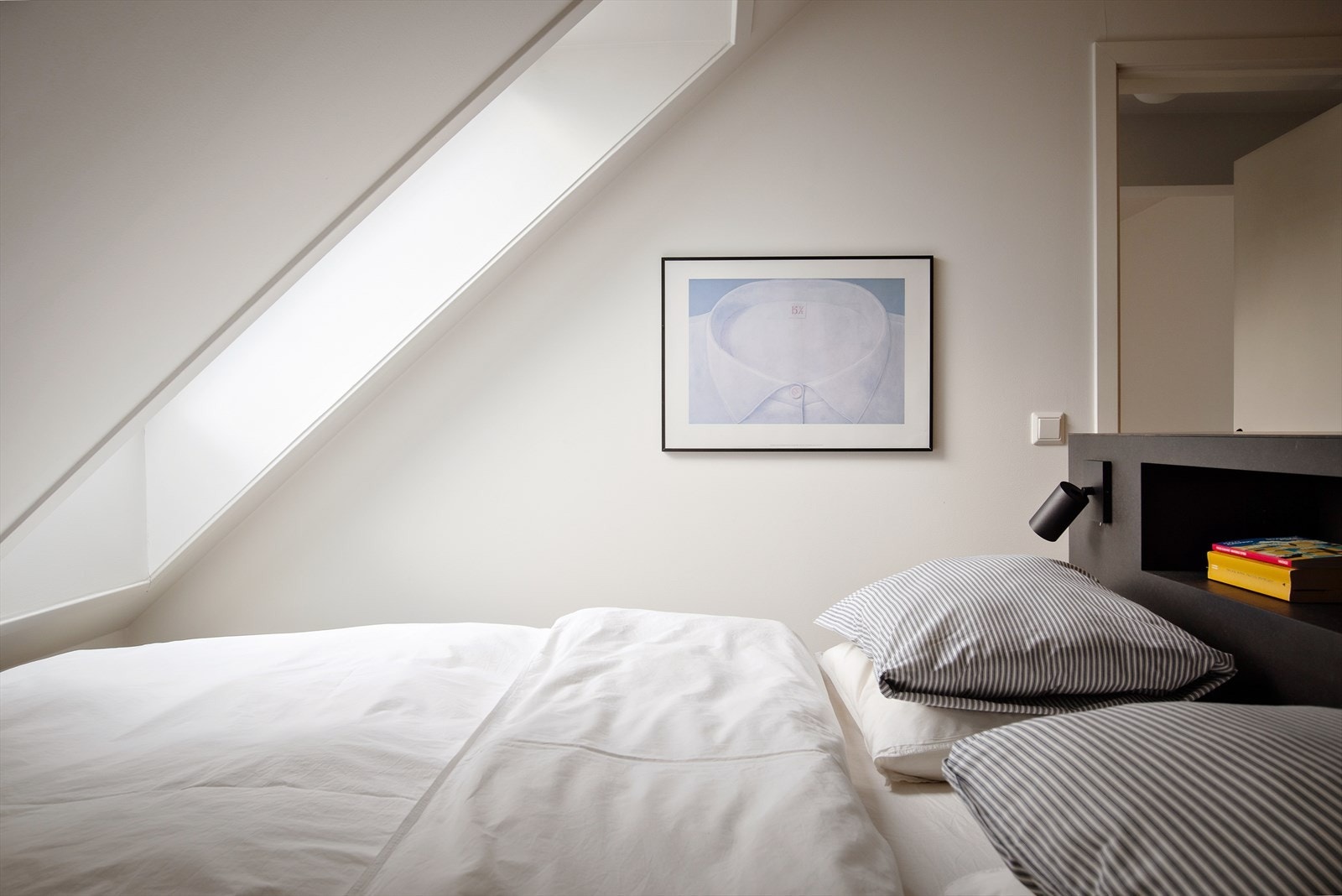 Lyst og fint hovedsoverom med skråtak og takvinduer Galleribilde