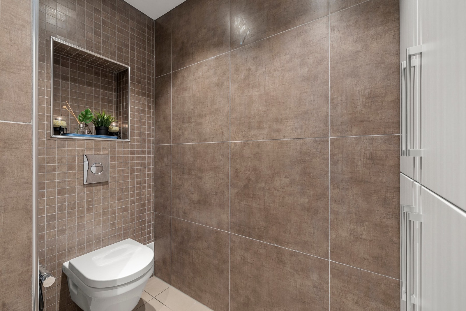 Badet inneholder servant, dusj, veggmontert toalett og har opplegg for vaskemaskin. Galleribilde