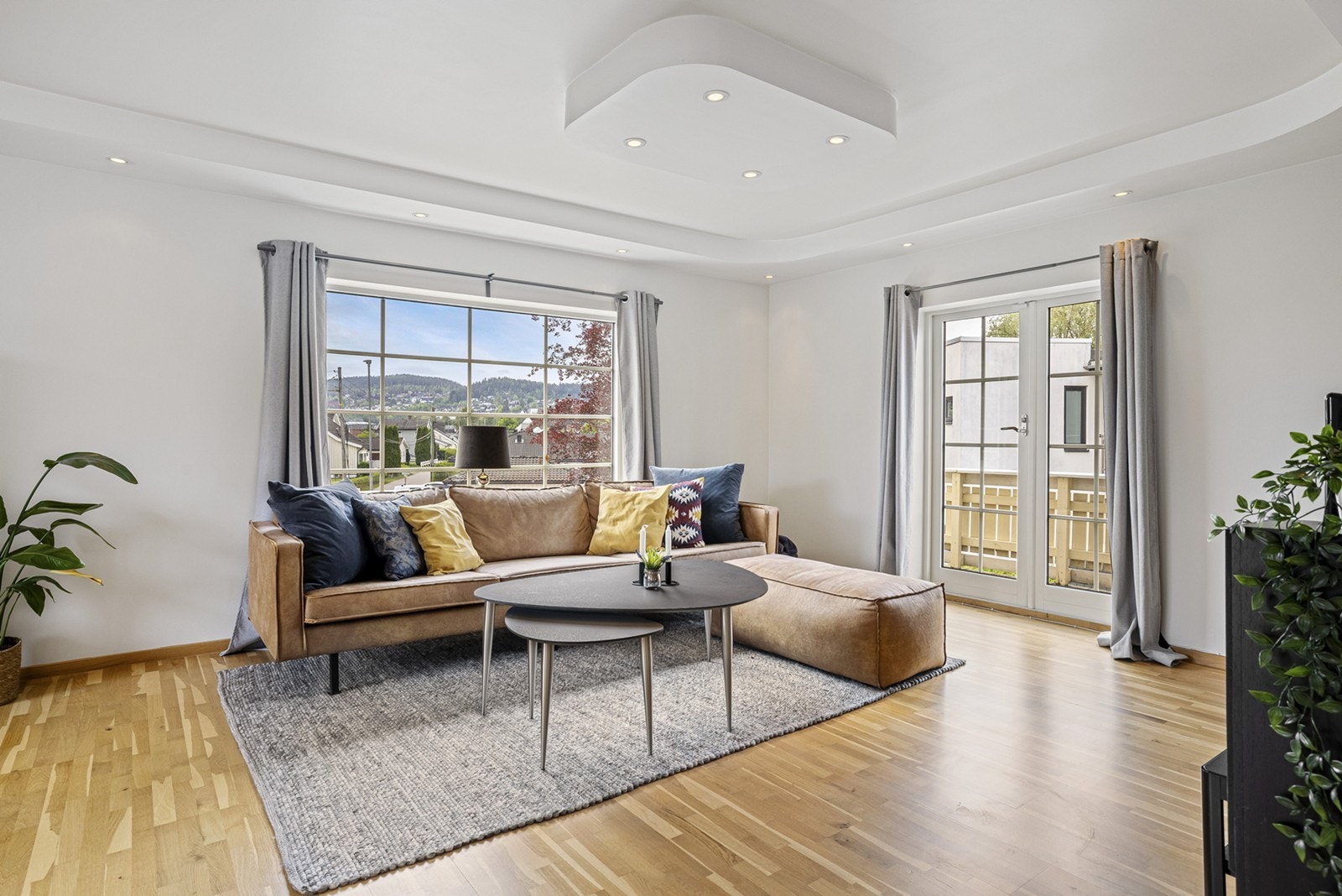 En lys og luftig hyggelig stue i andre etasje med parkettgulv og lyse, slette veggflater og downlights i himling. En glassdør fører ut til en balkong på ca. 5 kvm. Galleribilde