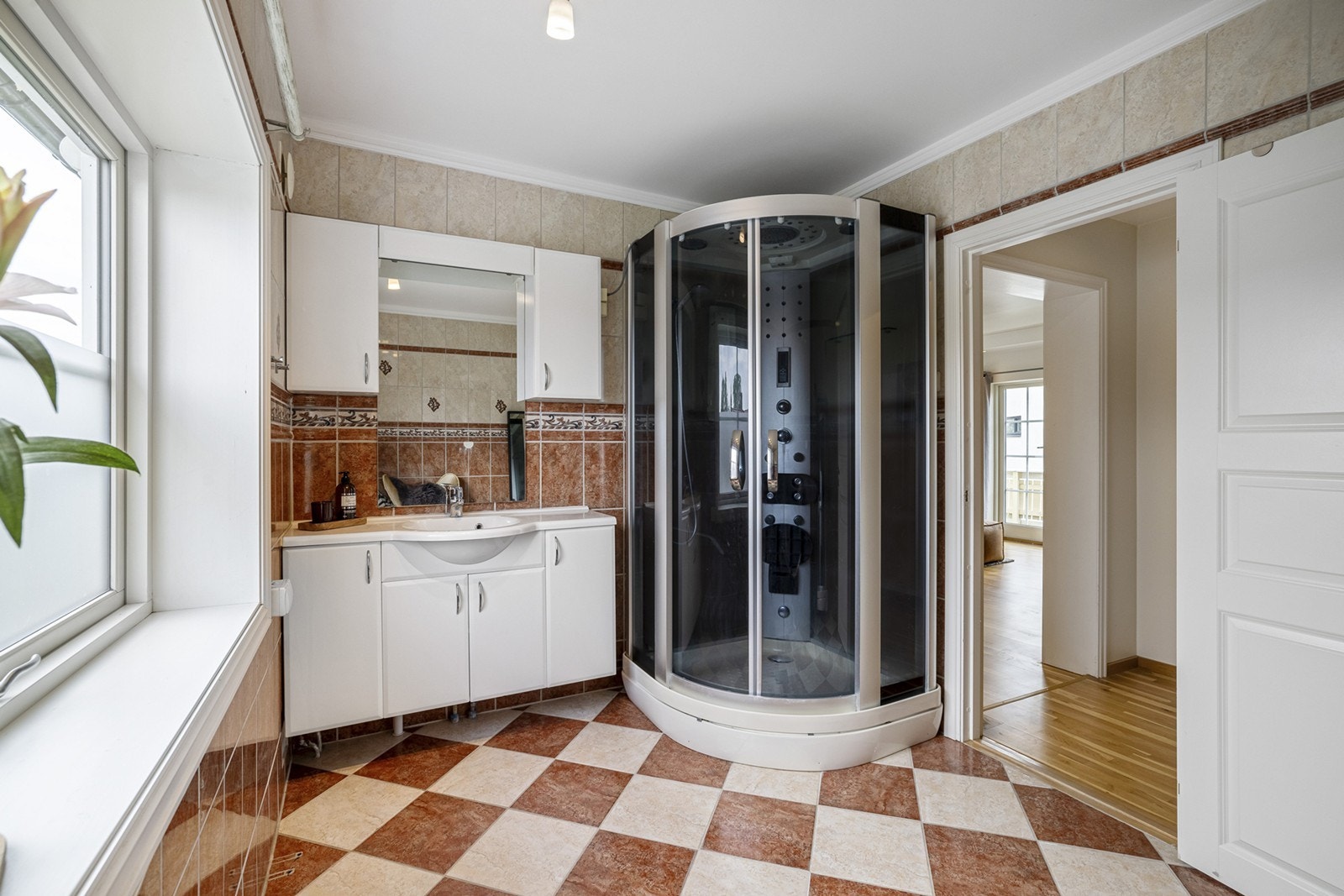 Et stort flislagt bad med gulvvarme og vindu. Innredningen består av et underskap/overskap, servant, speil, stikk og ett dusjkabinett. Her er det opplegg for vaskemaskin. Galleribilde