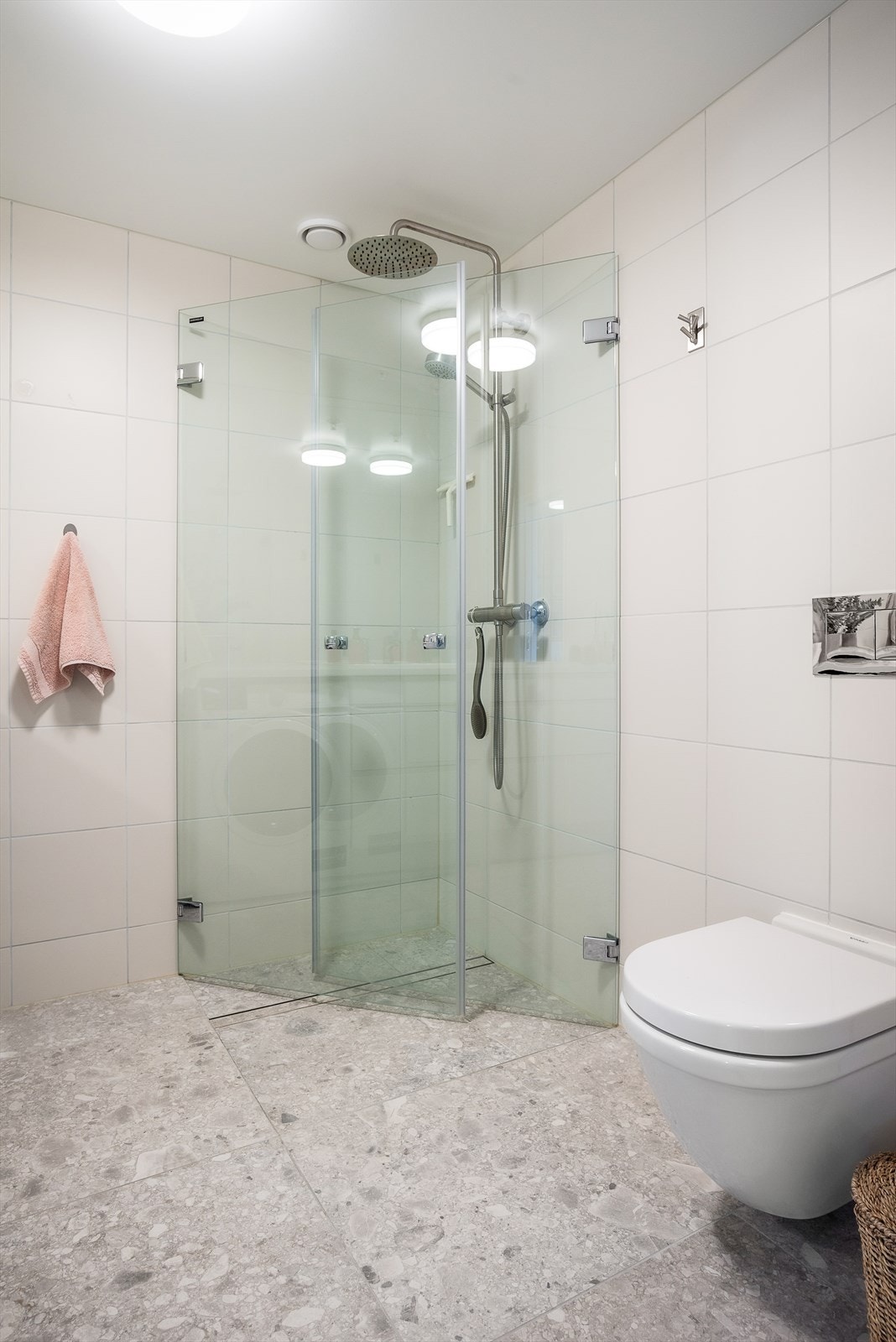 Det er vegghengt toalett med innebygd sisterne og dusjsone med innfelte dusjdører i herdet glass. Galleribilde