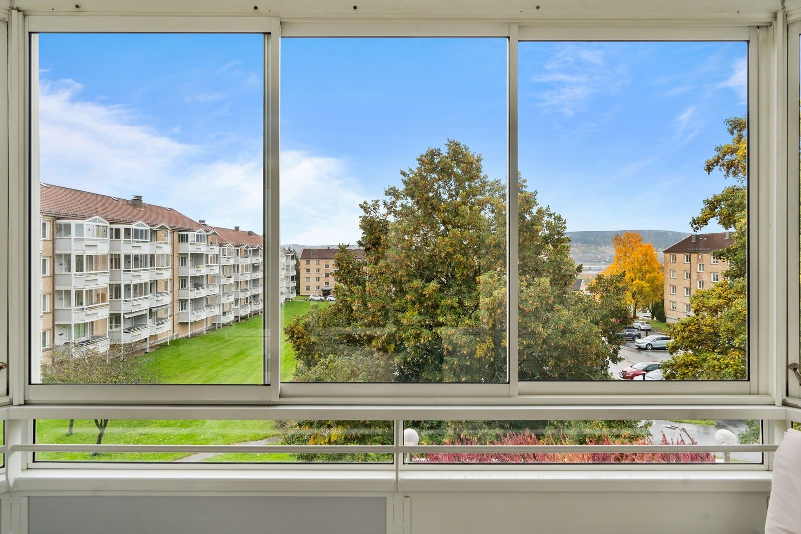 Fra balkongen er det flott utsikt over borettslagets felles uteområde med pent opparbeidet busker, grøntområder og asfalterte gangveier. Galleribilde