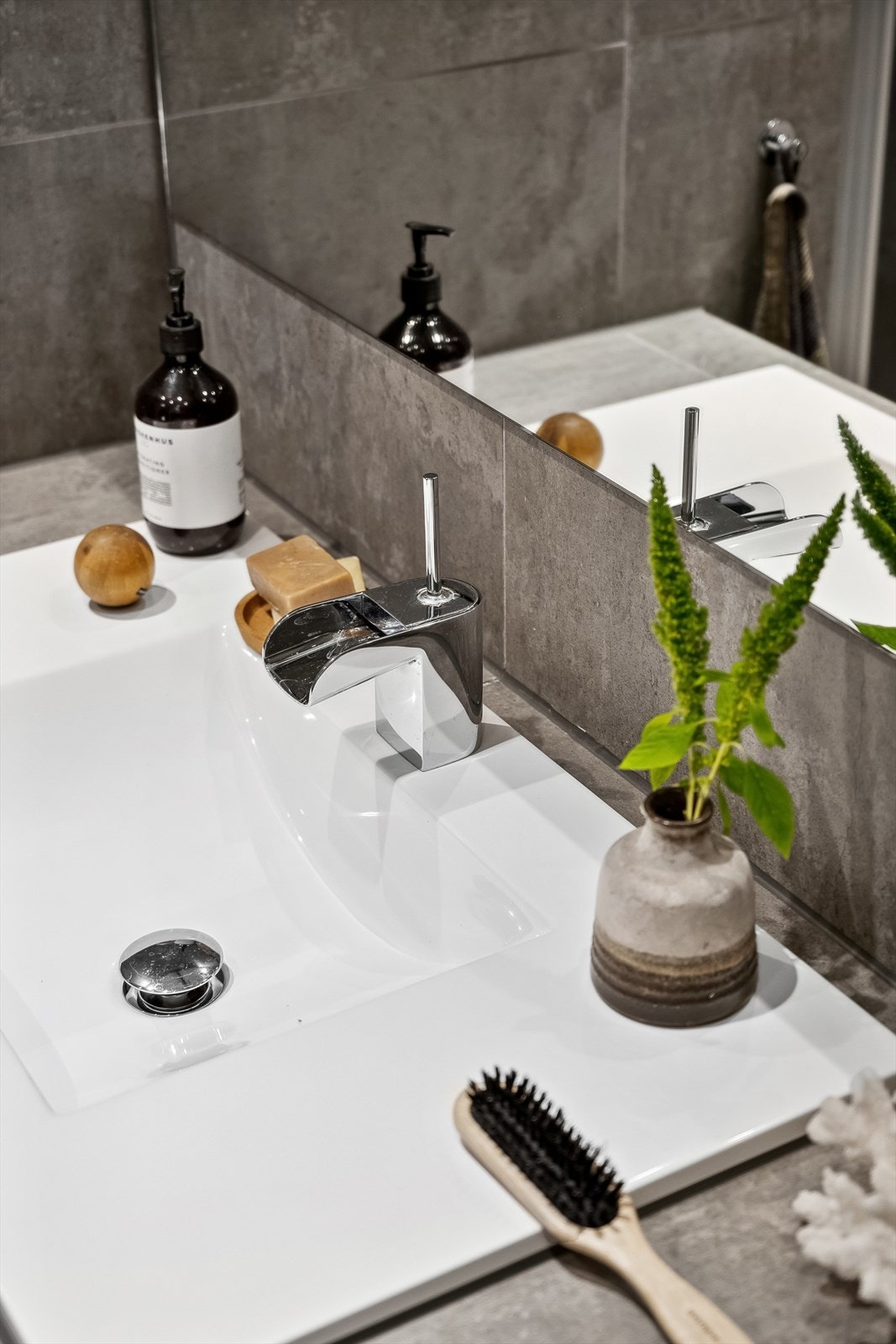 Det er en lekkert plassbygget flislagt benk med nedfelt servant, vegghengt klosett, dusjhjørne ved glassdører og opplegg for vaskemaskin. Galleribilde