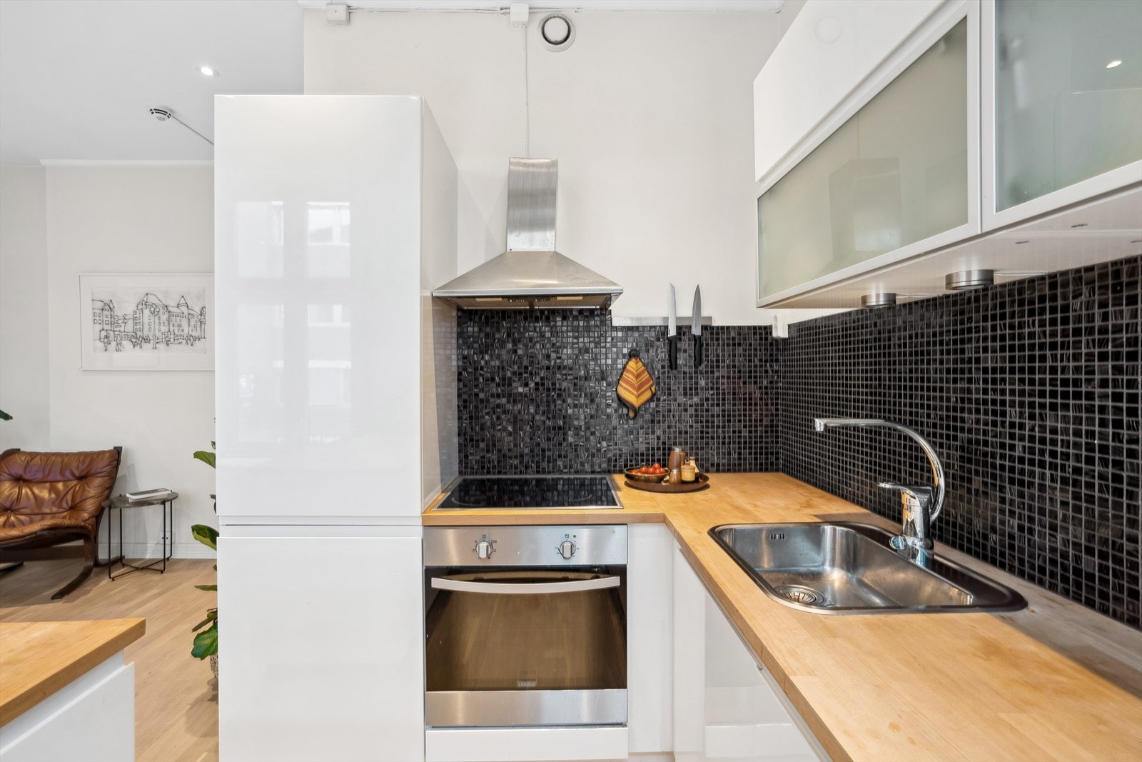 Kjøkkenet består av innredning med slette folierte høyglansfronter, heltre benkeplate med fliser over, enkel oppvaskkum, kjøkkenventilator i stål antatt med kullfilter, integrert koketopp, stekeovn, oppvaskmaskin og kjøl-/fryseskap Galleribilde