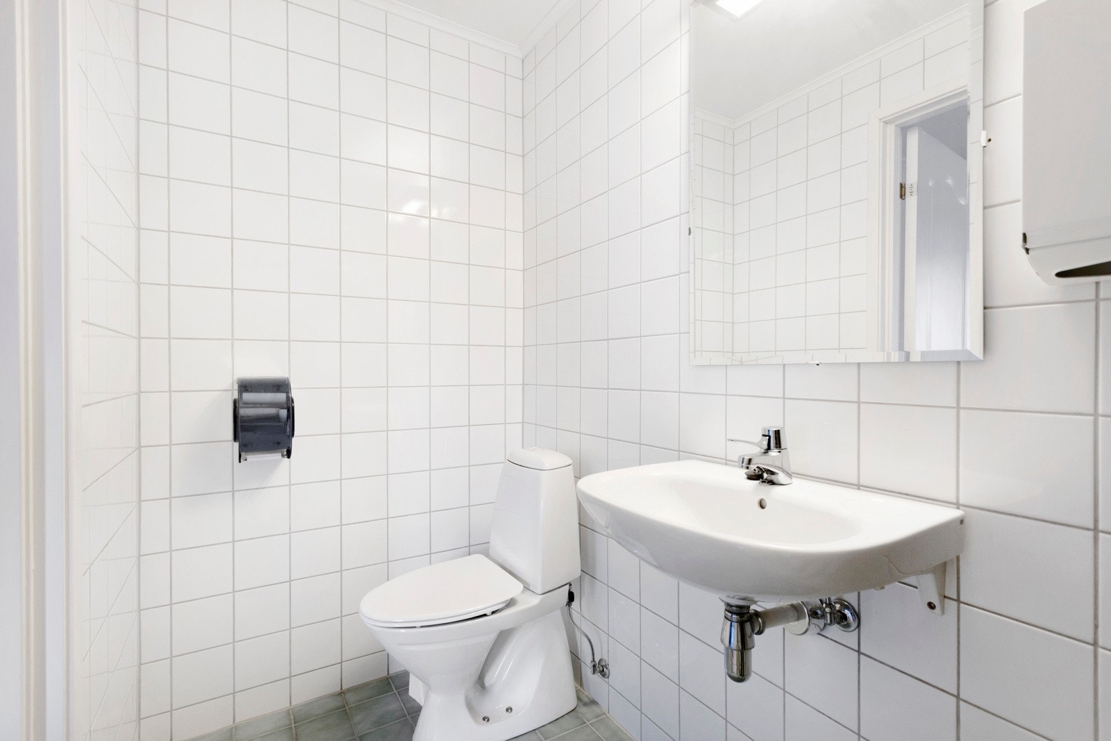 Toalett med flislagt gulv og flislagte veggflater. Galleribilde