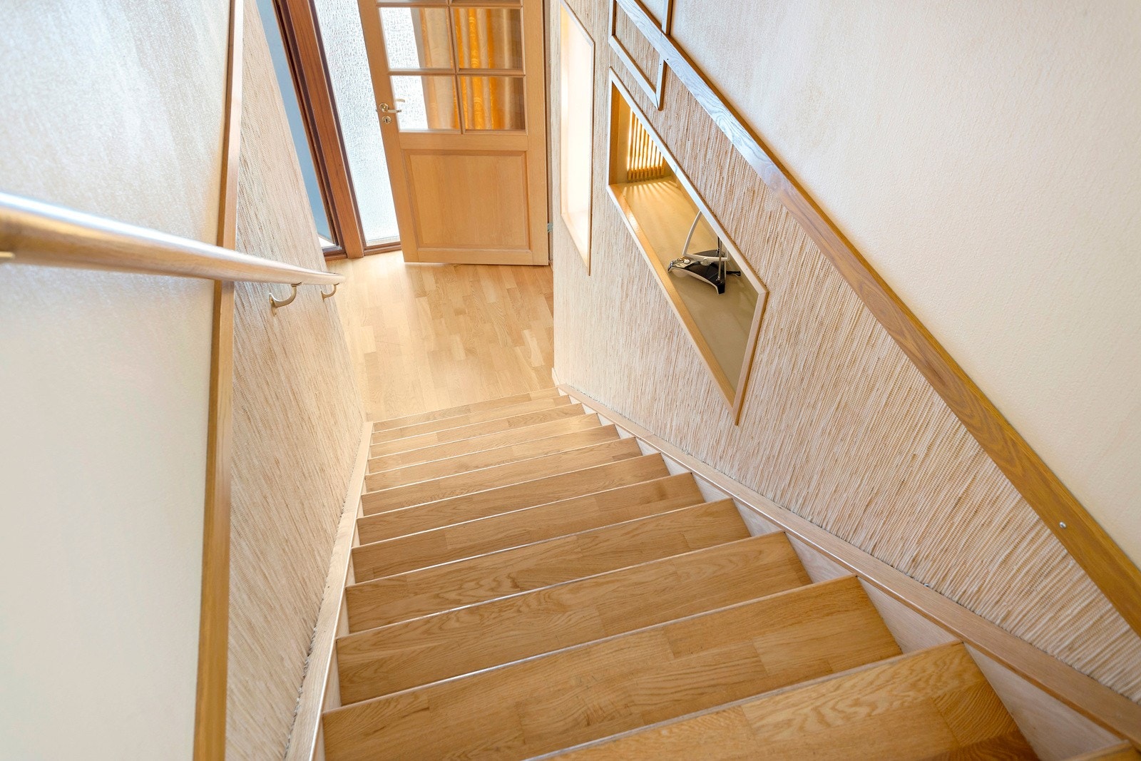 Trapp til 2. etasje med trinn av eik og lyssatt nisjehylle. Galleribilde