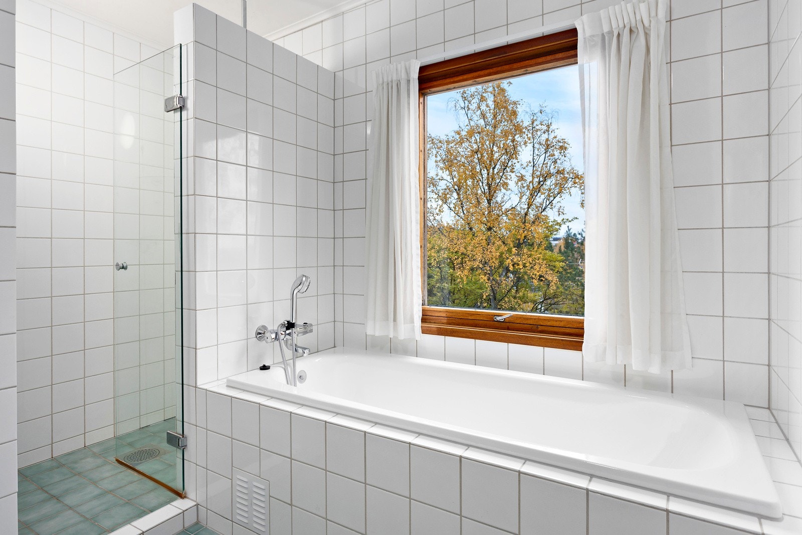 Baderommet har flislagt gulv og flislagte veggflater og innfliset dusj og badekar. Galleribilde