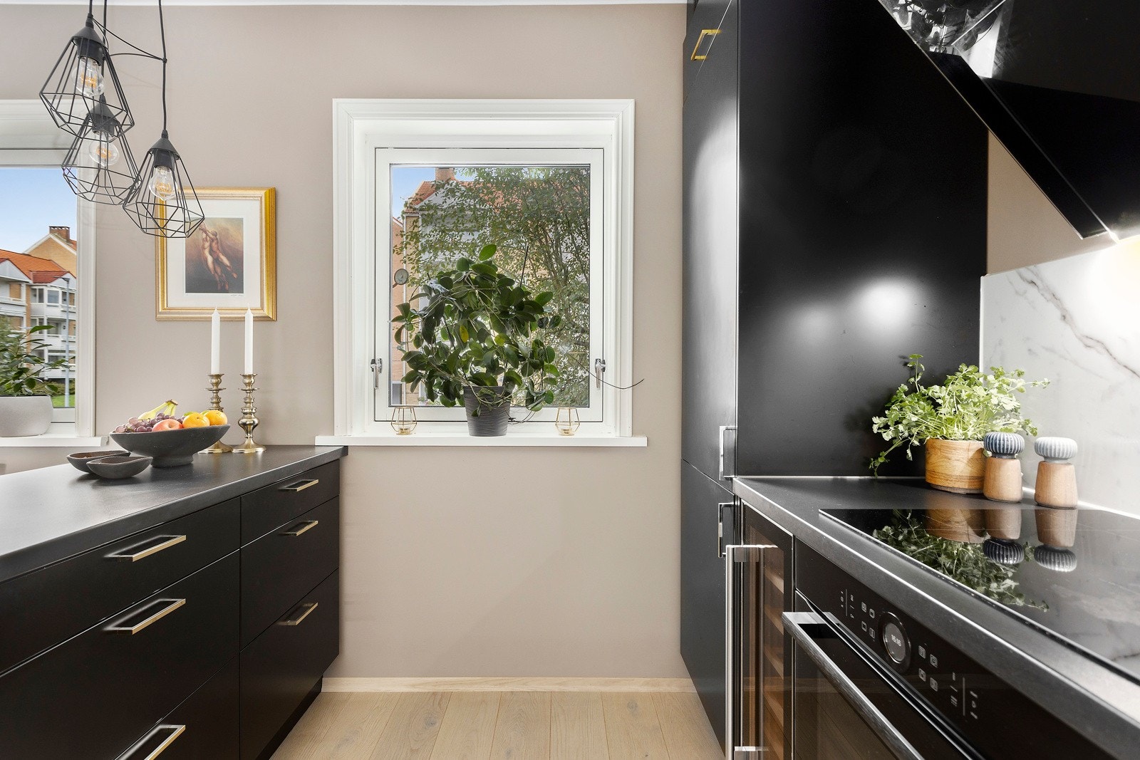 Kjøkkenet har innredning med glatte fronter i sort, som utgjør en stilfull kontrast til den lyse og luftige estetikken i rommet Galleribilde