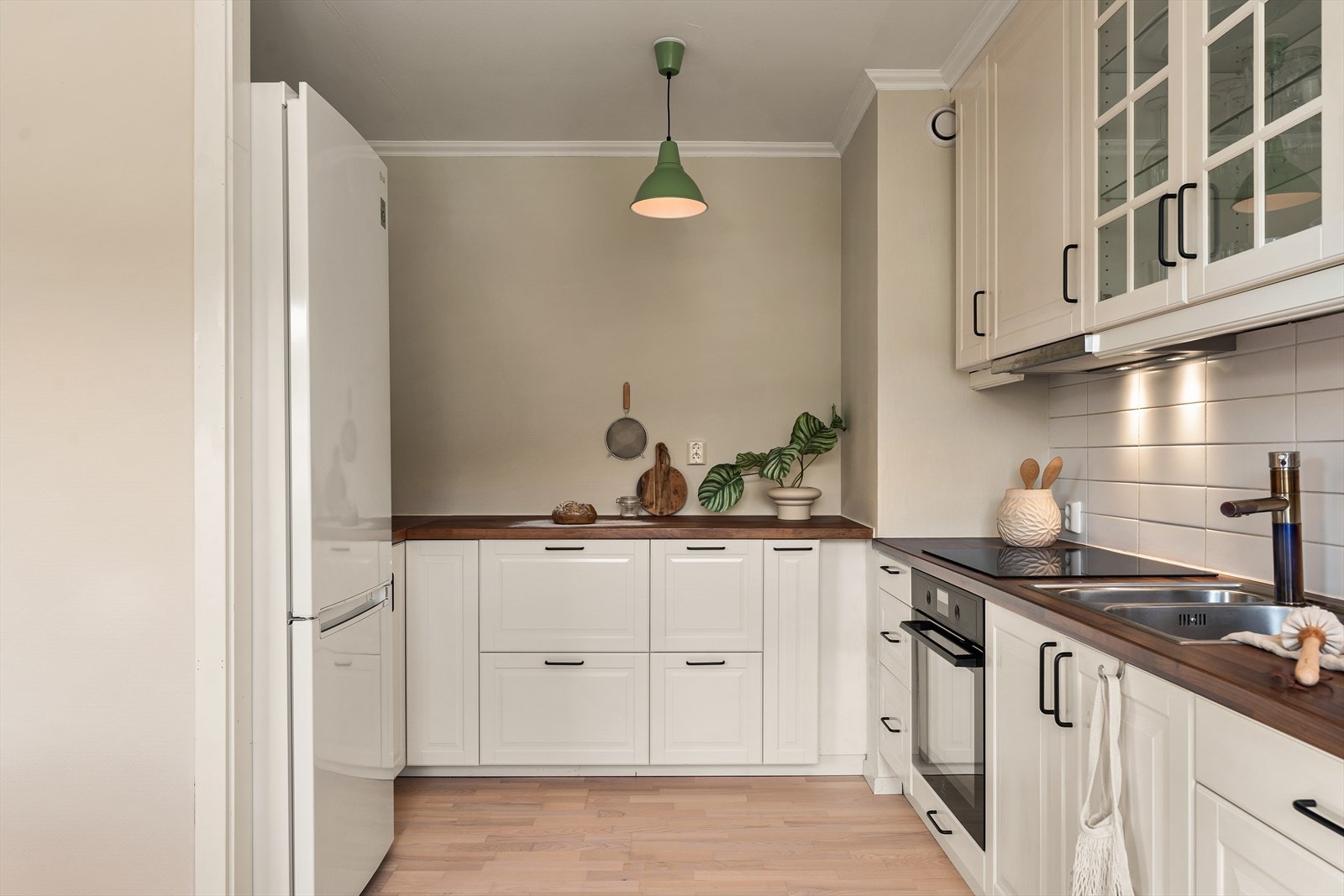 Kjøkkenet inneholder laminert benkeplate. Profilerte hvite fronter. Fliser mellom benkeplate og overskap. Opplegg for oppvaskmaskin. Overskap til himling. Integrert stekeovn (ny i 2024) og induksjonstopp. Kjøkkenventilator med kullfilter Galleribilde