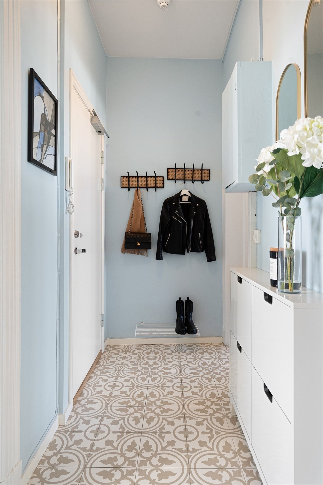 Entréen er lys og fin med flislagt gulv. Plass for veggoppheng til klær og vesker. Sikringsskap og porttelefon. Galleribilde