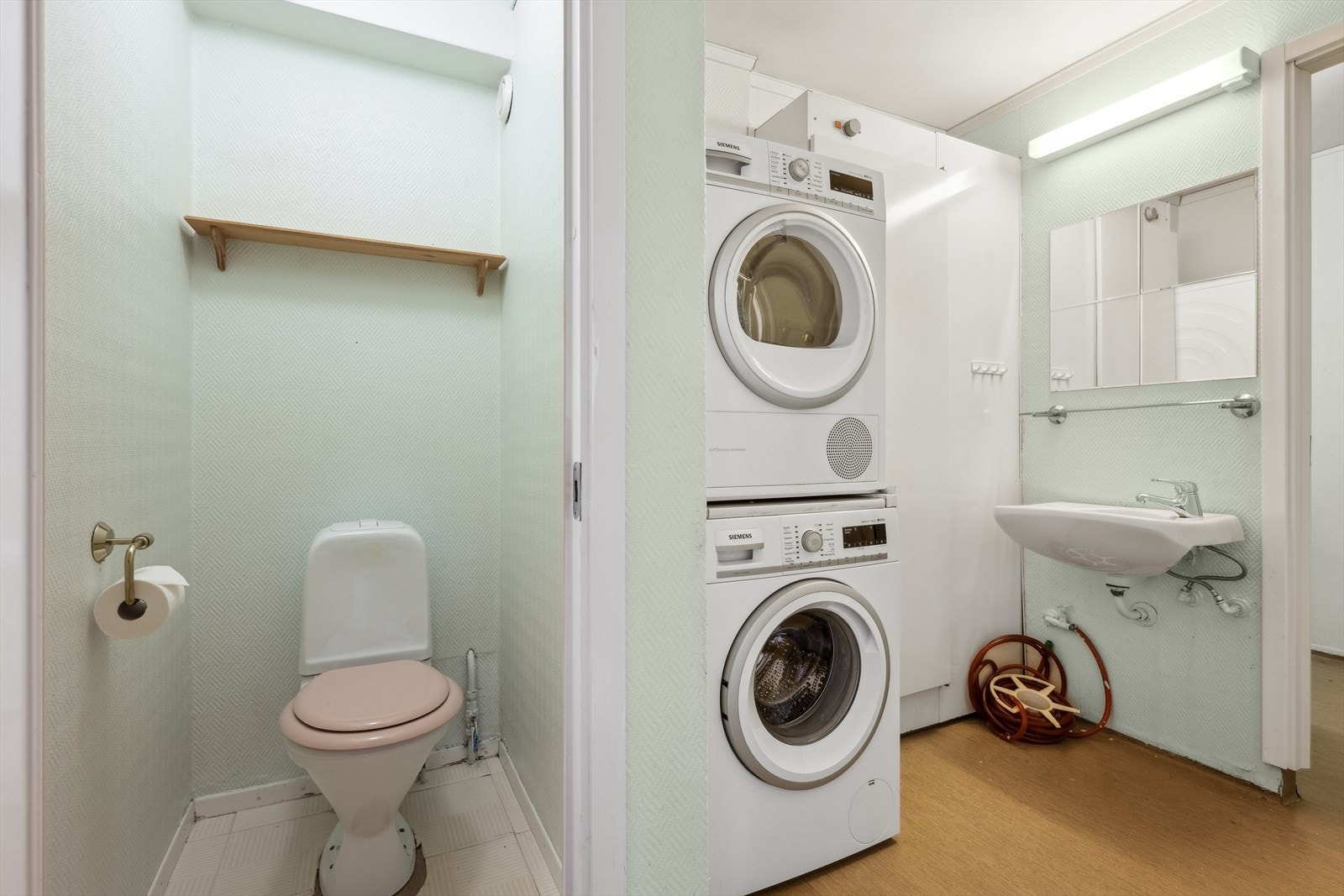 Badet er eldre med en tredeling med separat wc, vaskerom og bad. Wc med toalett. Vaskerom med bereder, servant og opplegg for vaskemaskin. Bad med servant og dusj. Galleribilde