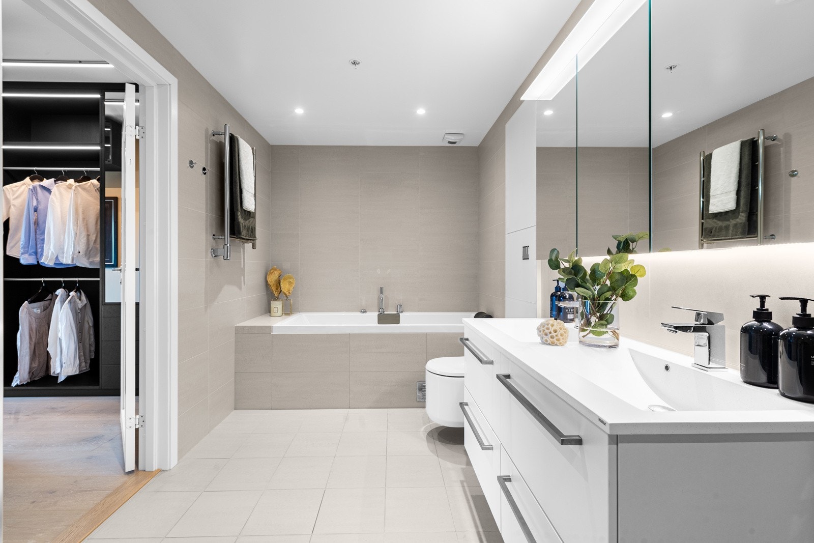 Baderommet i mastersuiten er innredet med et innfliset badekar i den ene enden av rommet, og et dusjhjørne med regnfallsdusj, hånddusj og innfellbare glassdører i den andre enden. Galleribilde