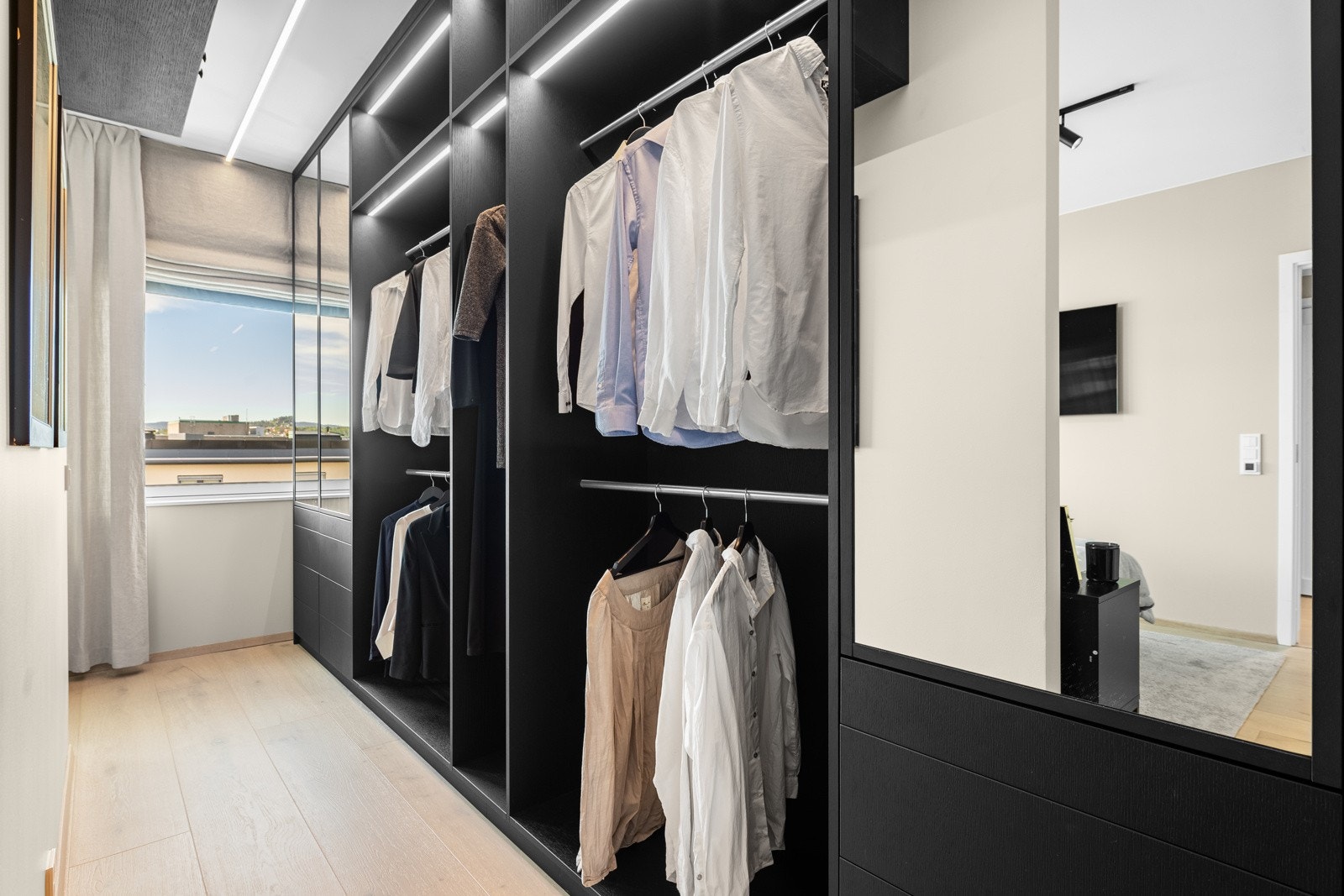 Garderoben har sorte fronter, speil, belysning og flott innredning Galleribilde