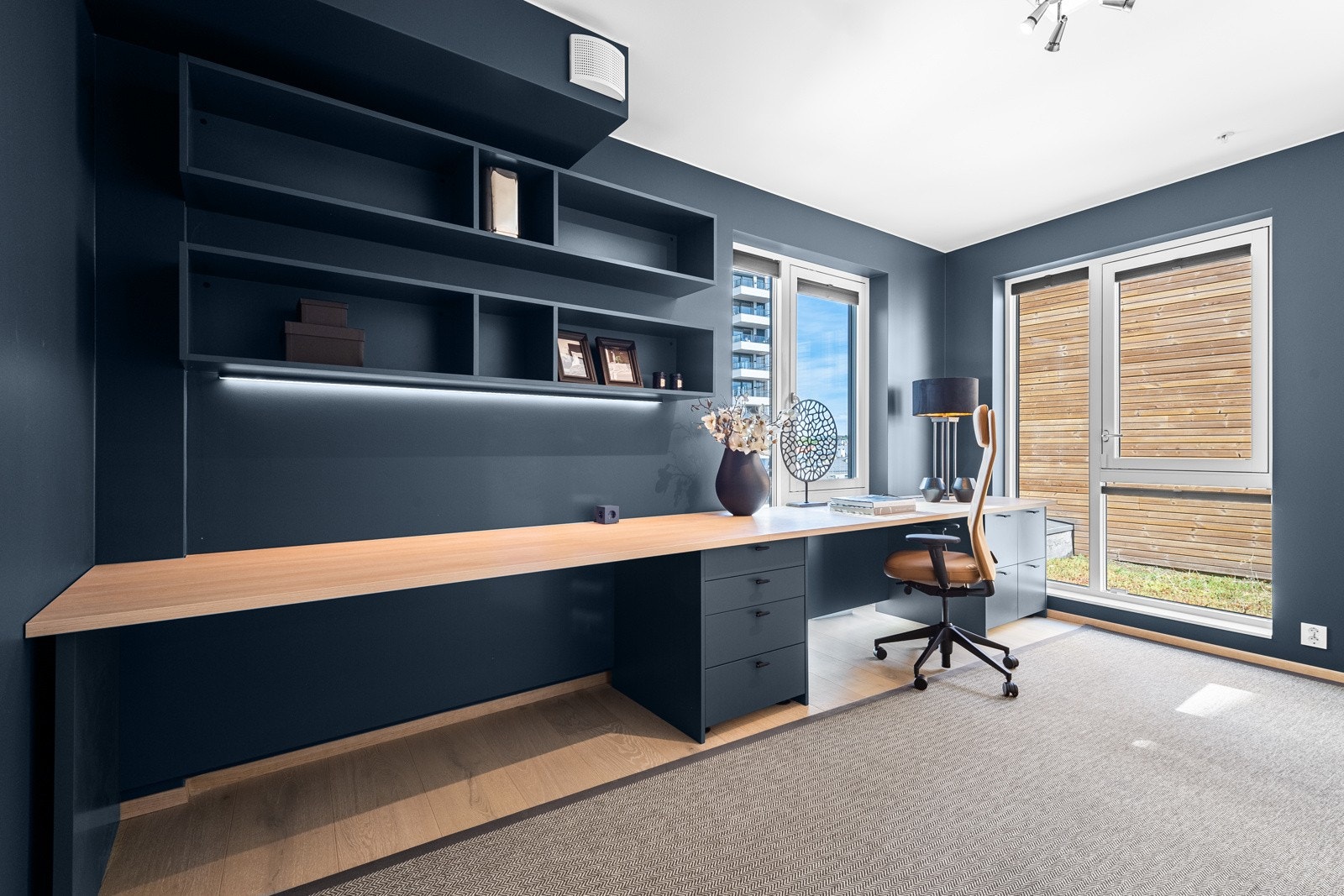 Rommet har plassbygd skrivepult langs en hel vegg og en takhøy skyvedørsgarderobe langs motsatt vegg Galleribilde