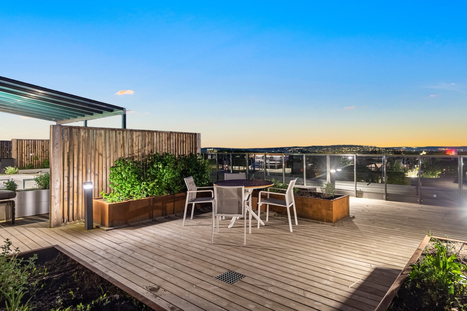 Felles takterrasse med loungegrupper til felles glede, pergola i tre, flere plantekasser og rekkverk i glass Galleribilde