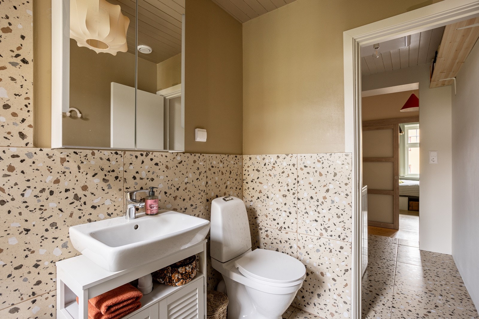 Baderommet har en sjarmerende lys innredning med ovenpåliggende servant, speilskap med integrert belysning over og gulvstående toalett. Galleribilde