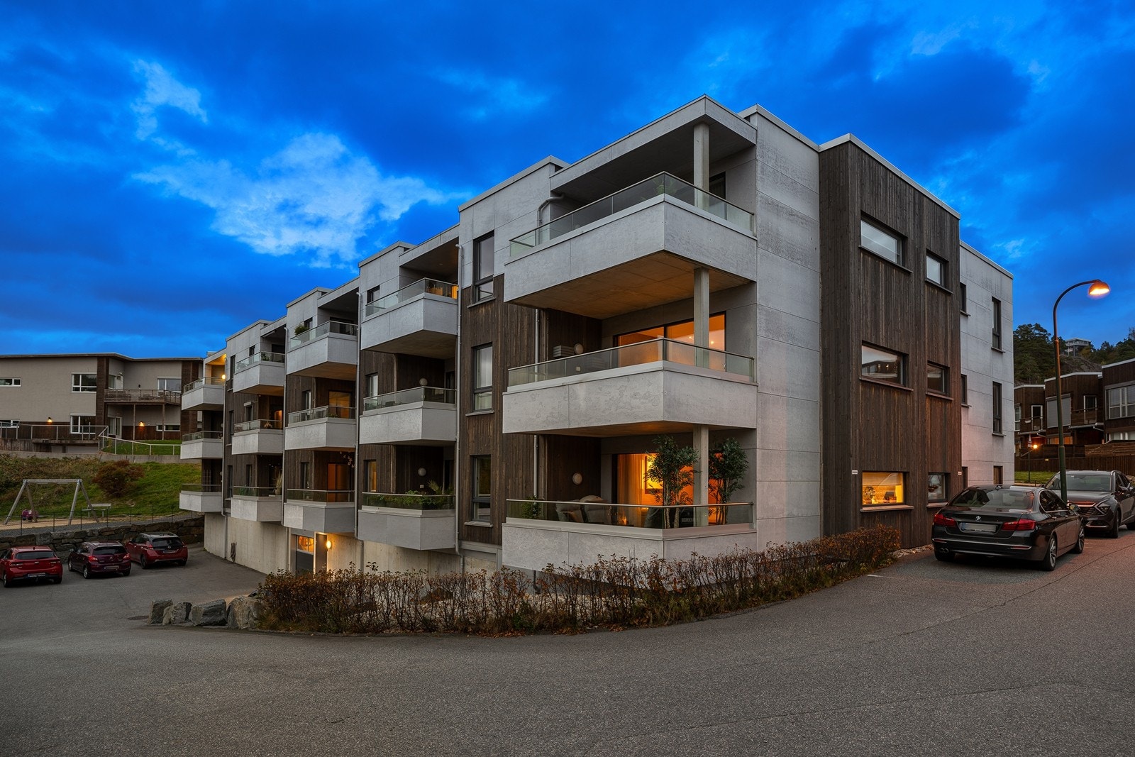 Leiligheten har en fin beliggenhet i byggets 1. etasje med direkte adkomst fra bakkeplan. Dette er en endeleilighet hvor alle rom med unntak av vaskerom har god tilgang til naturlig dagslys. Den aktuelle leiligheten er den nærmeste på bildet. Galleribilde