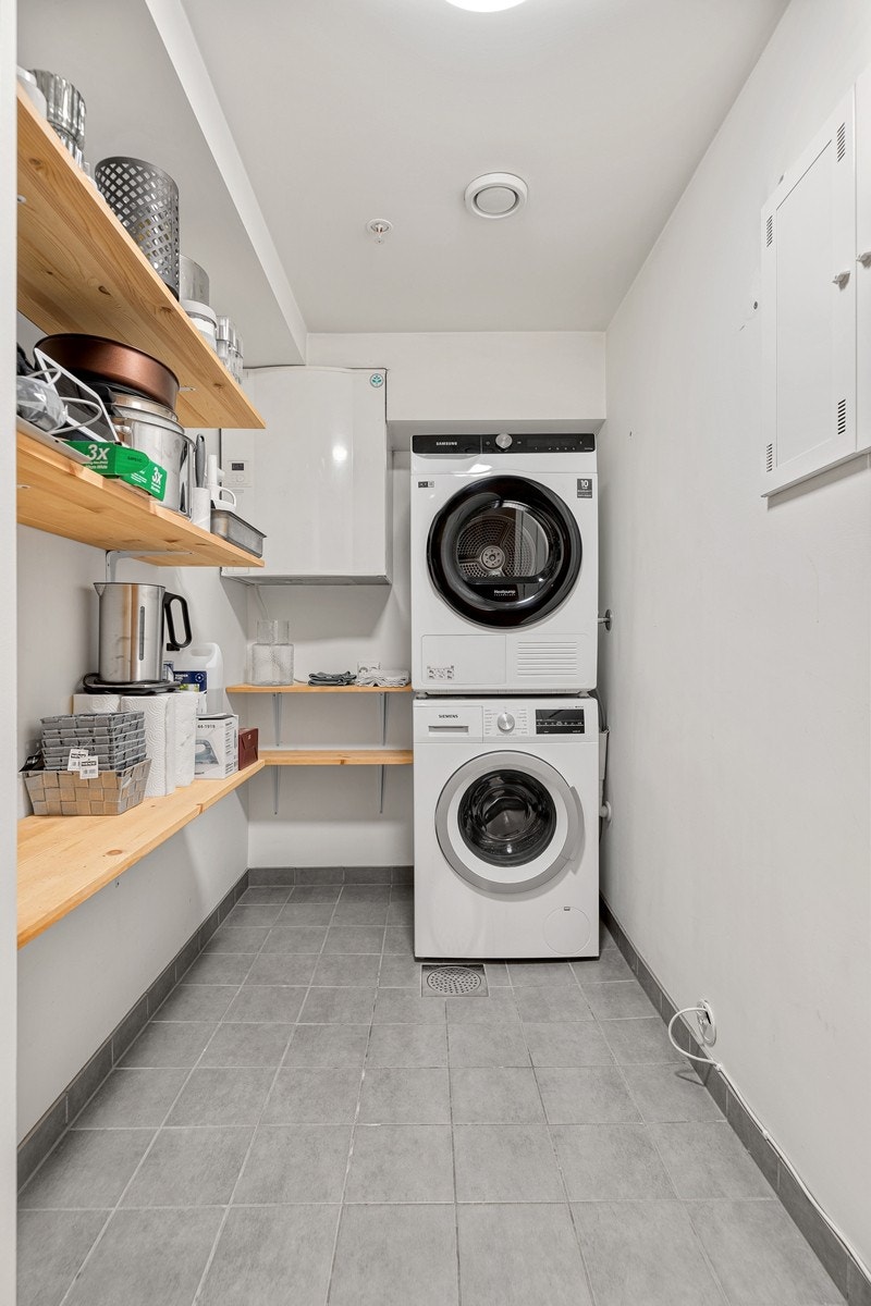 Praktisk vaskerom med gode lagringsmuligheter og opplegg til vaskemaskin og tørketrommel. Det er flislagt gulv med sluk, og malte veggflater. Galleribilde