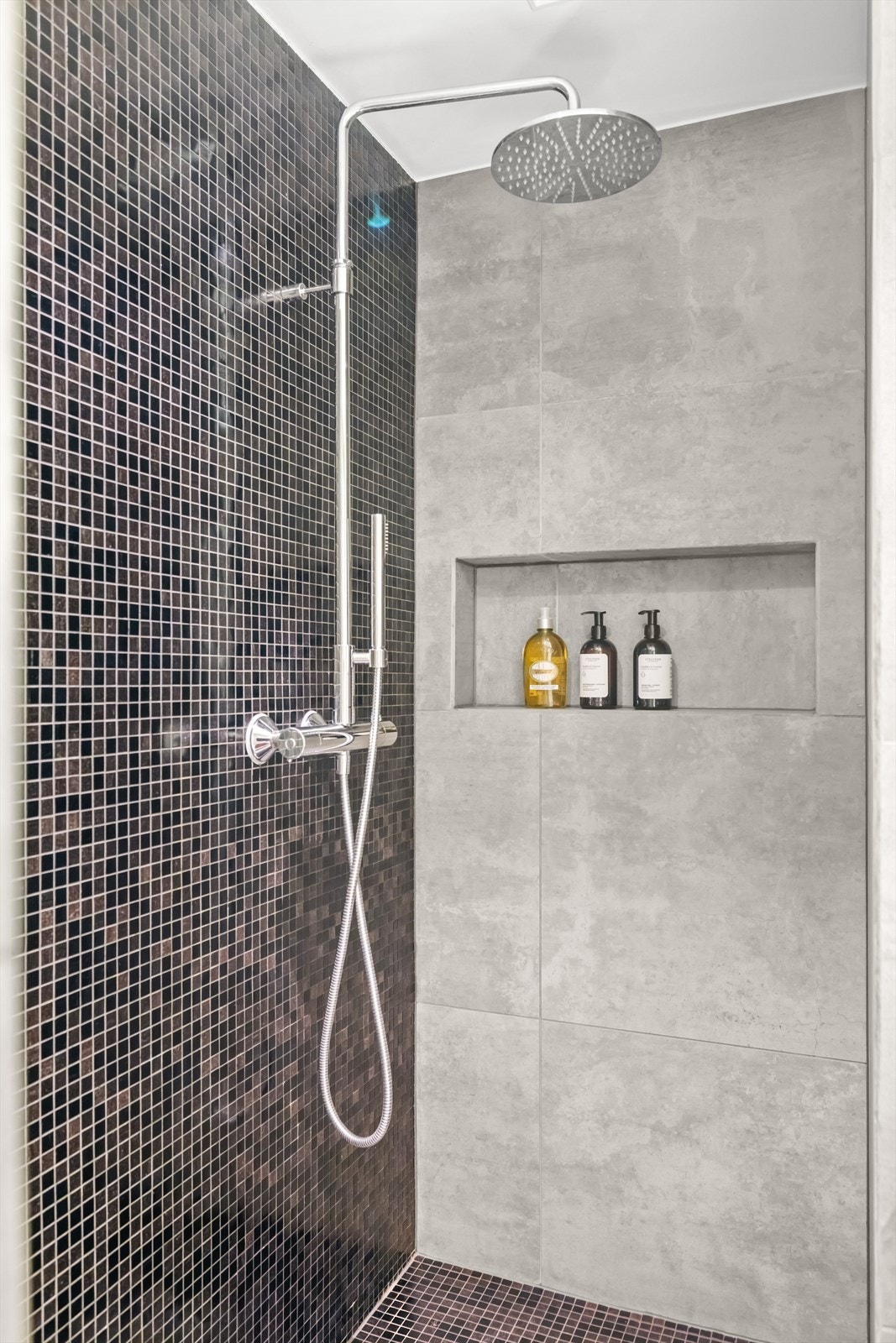 Romslig dusj med regnfallsdusj og nisje for såpe og sjampo. Galleribilde