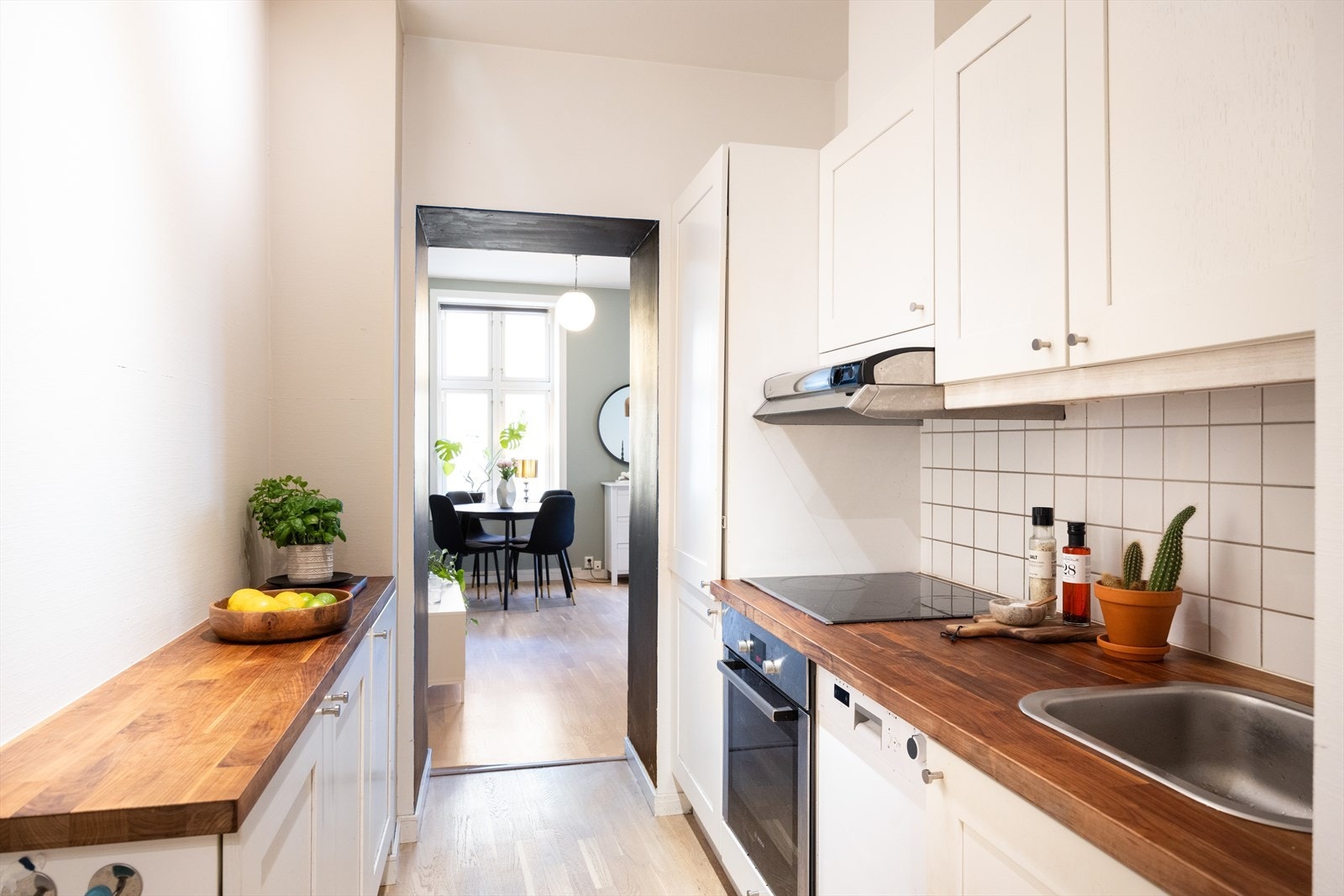 Kjøkkeninnredning består av hvite profilerte fronter og benkeplate av laminat med nedfelt vask og skyllekum. Galleribilde