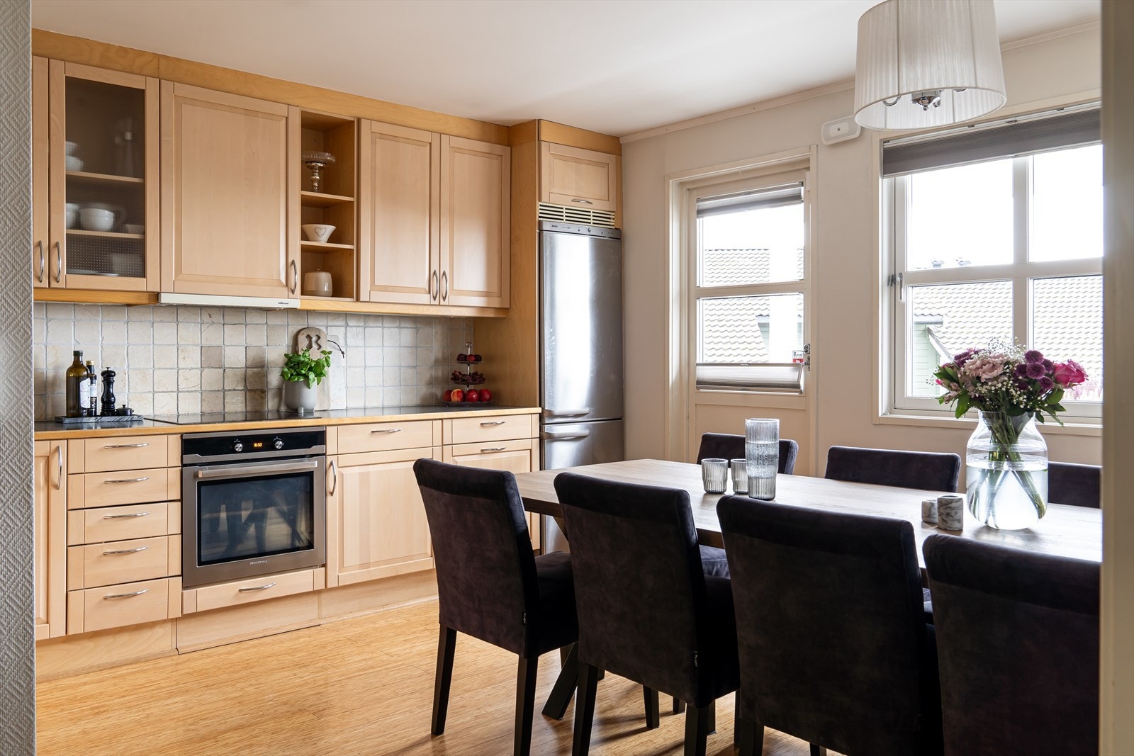 Lyst kjøkken med takhøye skap, profilerte fronter i lakkert heltre og vitrinedører som gir et klassisk uttrykk. Galleribilde