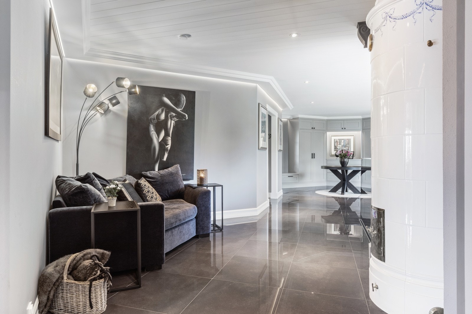 Romslig entré/hall med leseavdeling og kakkelovn. Belysning innfelt oppunder tak. Galleribilde