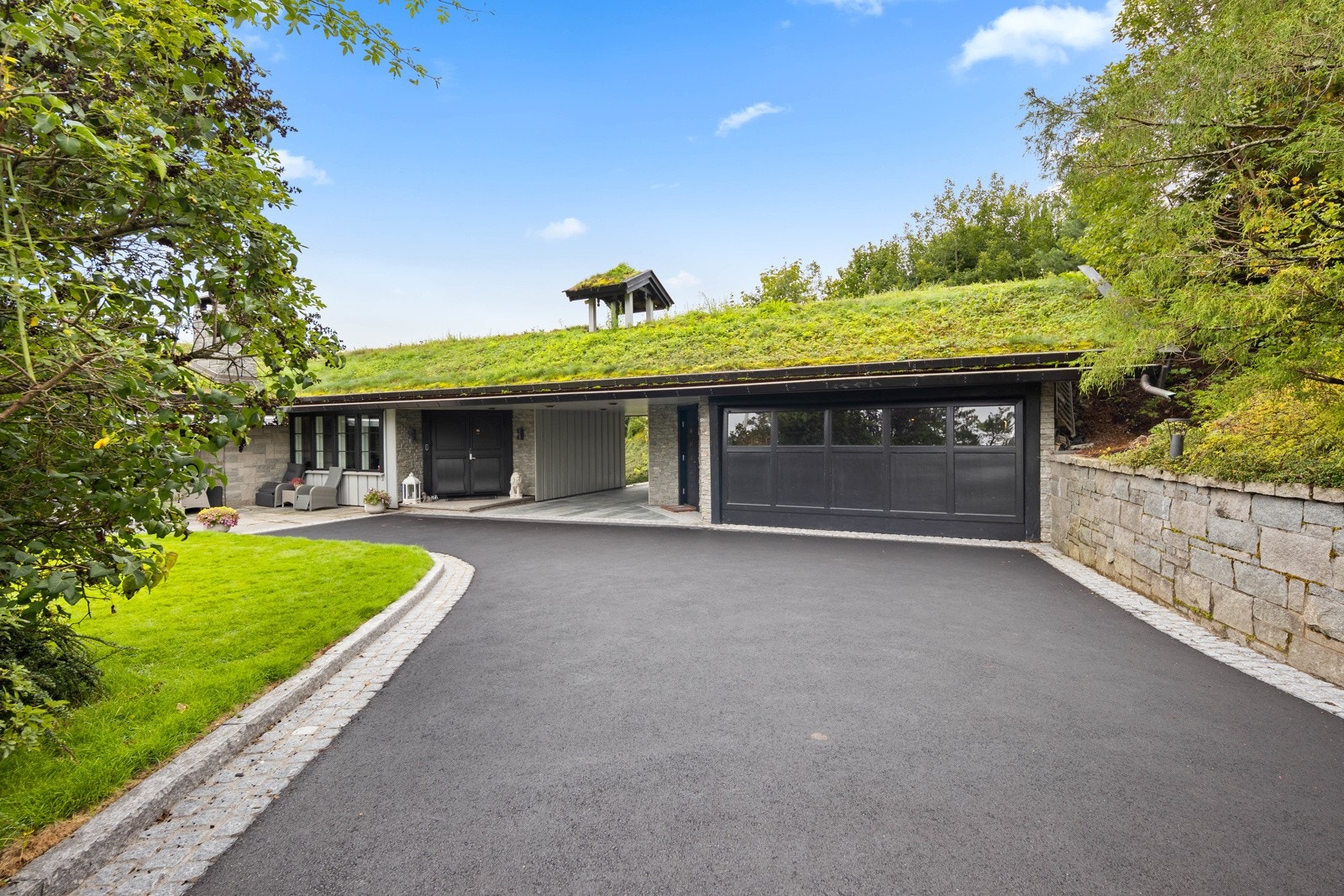 Gårdsplassen er omrammet med brostein, skifer mellom hus og garasje utført august 2023. Galleribilde