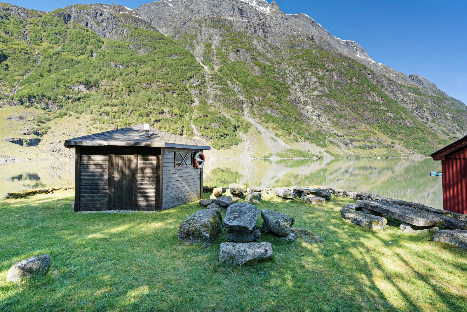 Området er pent opparbeidet med plen, gråsteinsmurer og benker Galleribilde