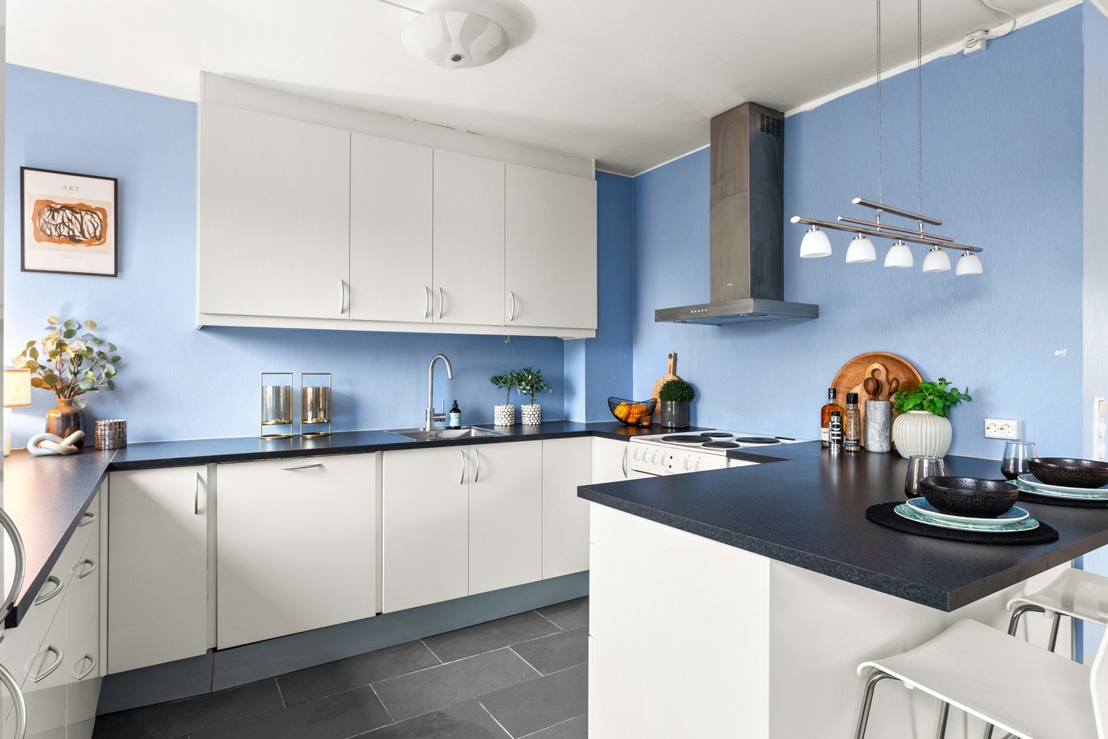 Én vegg har overskap opp til taket, så her får man gode arbeidsflater og rikelig med plass til kjøkkenutstyret. Galleribilde