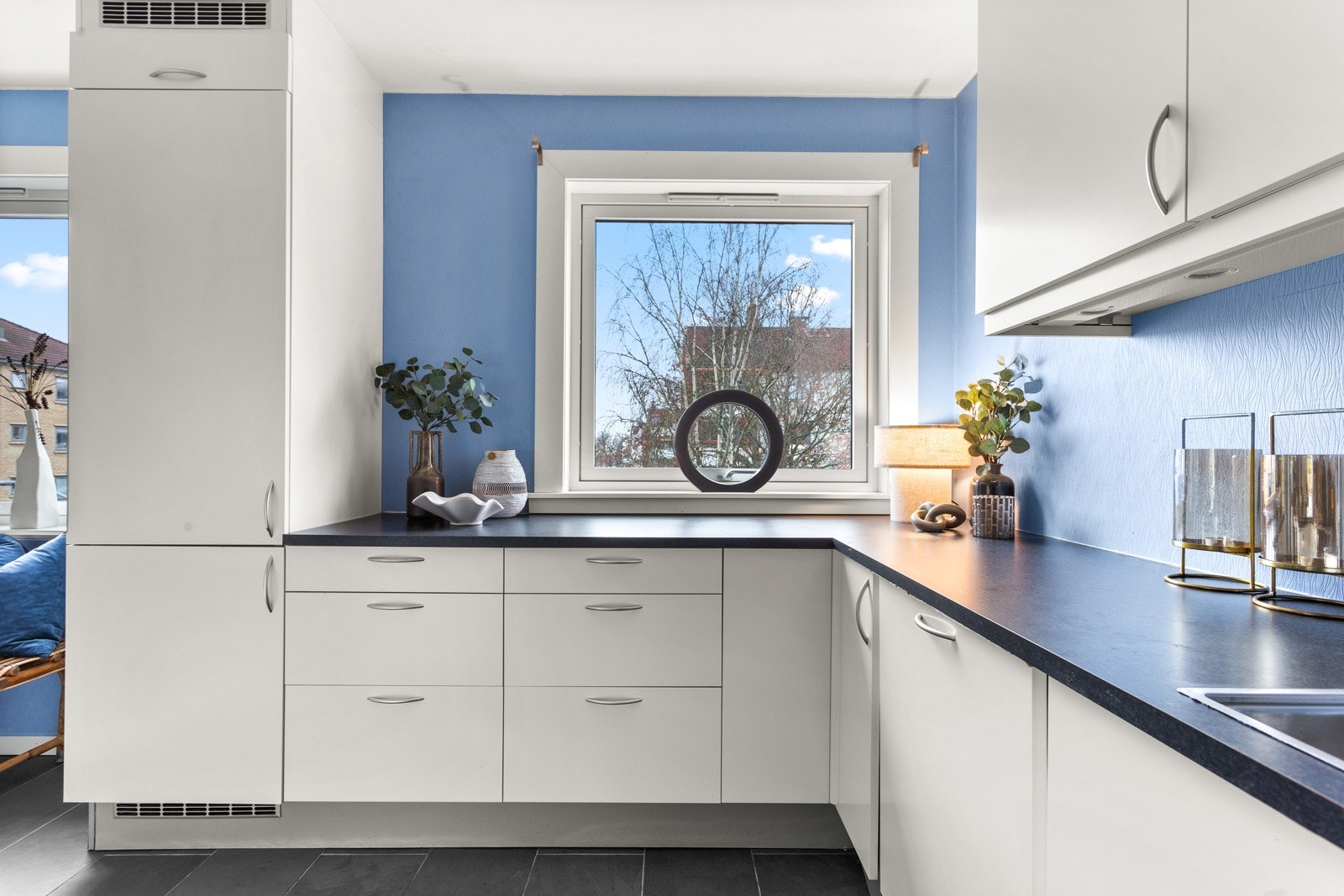 Innredningen har slette fronter med demping, sort benkeplate i laminat og nedfelt oppvaskkum i rustfritt stål. Galleribilde