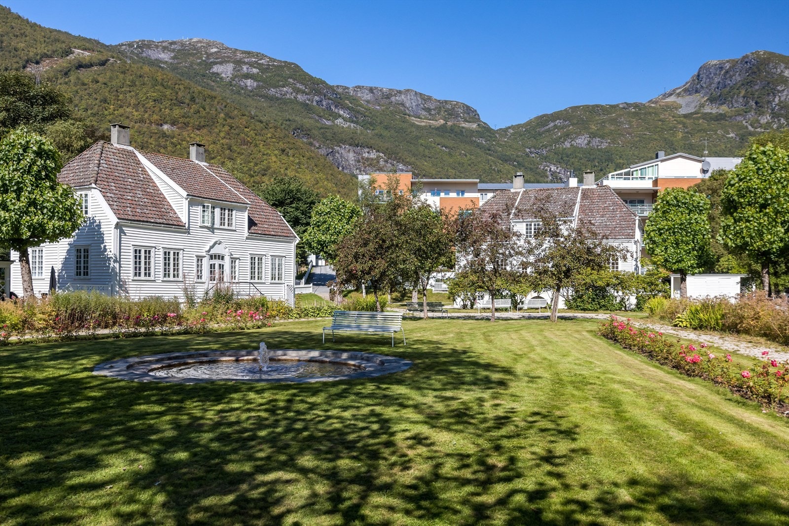 Bustaden er skjerma mot fellesarealet med busker og tre. Galleribilde
