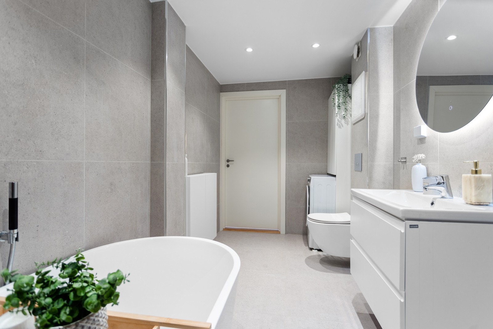 Vegghengt toalett med skjult sisterne. Badet har opplegg for vaskemaskin. Galleribilde