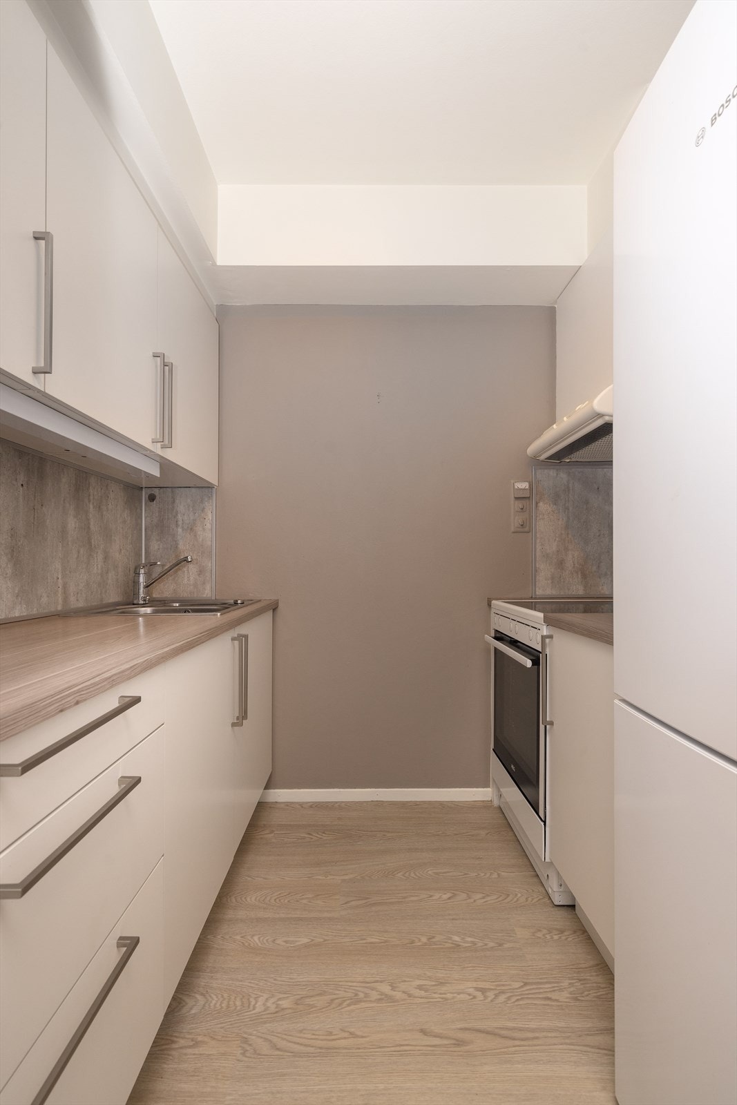 Kjøkken har lys innredning med slette fronter og benkeplate i laminat. Det er ventilator med avtrekk ut i skap over stekesone. Galleribilde