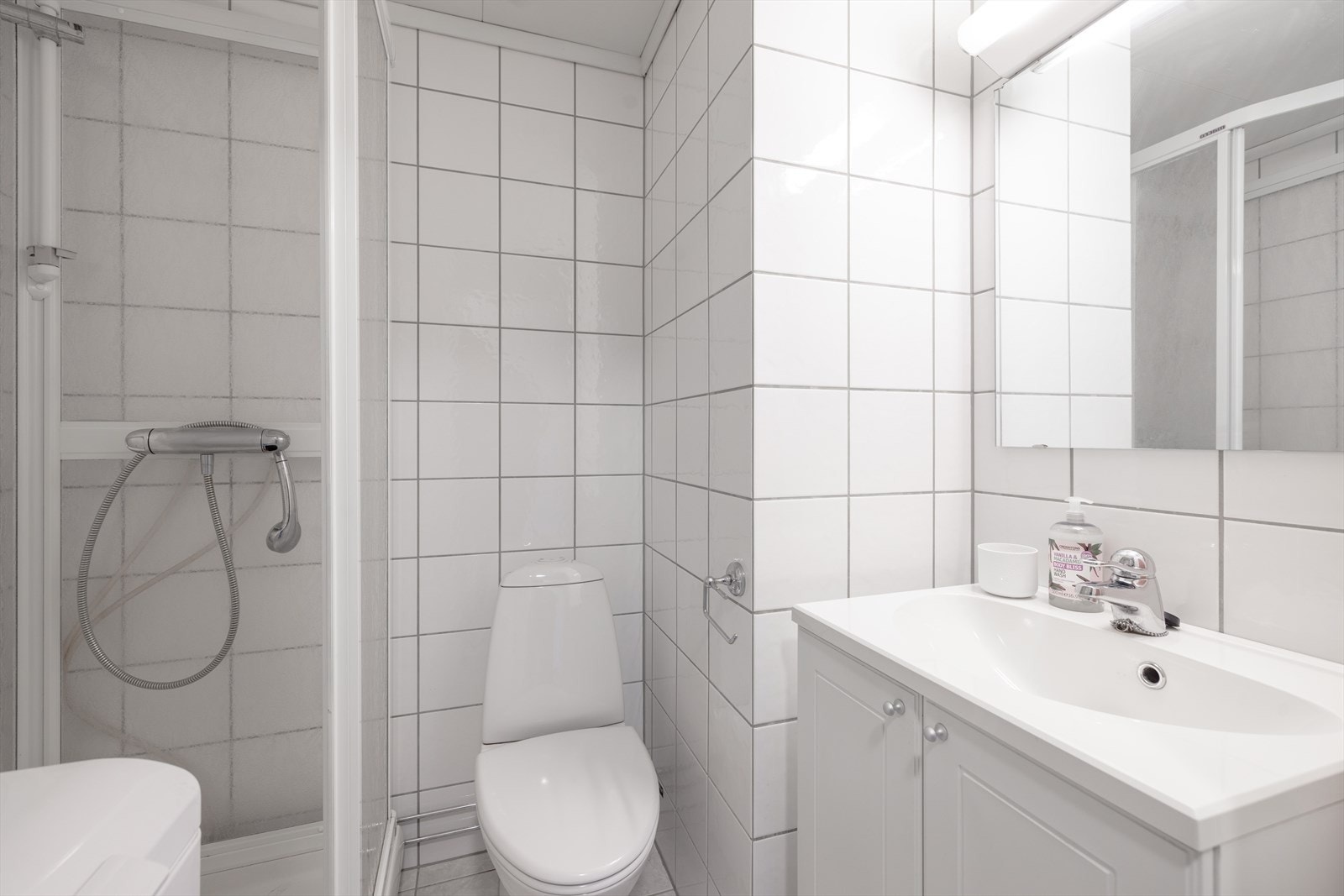 Badet er innredet med toalett, dusjkabinett og servantinnredning med underskap, speil og overlys. Det er opplegg for vaskemaskin. Galleribilde