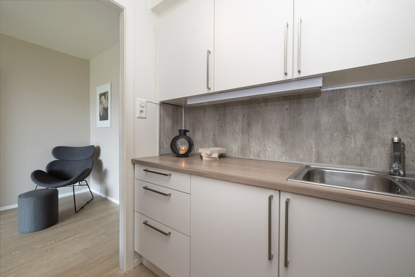 Pent HTH-kjøkken med plater over benk og belysning Galleribilde