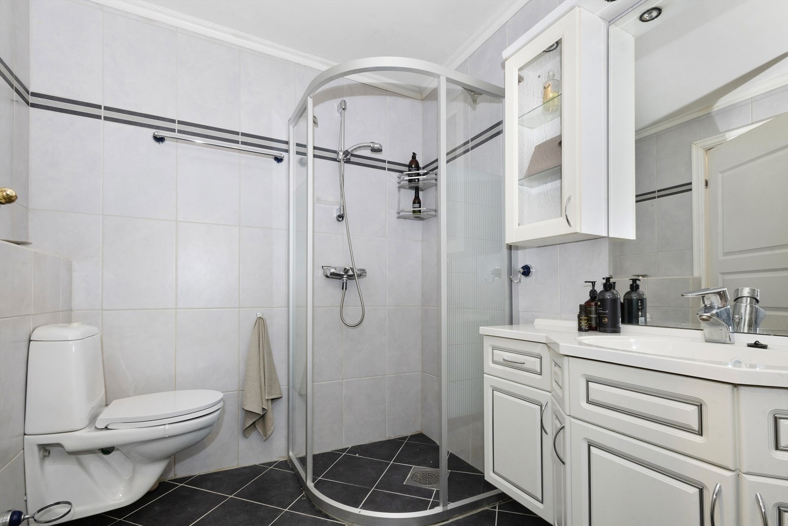 Badet er innreidd med vegghengt klosett, dusjhjørne, servant i underskap, vamtvassberedar og opplegg for vaskemaskin Galleribilde