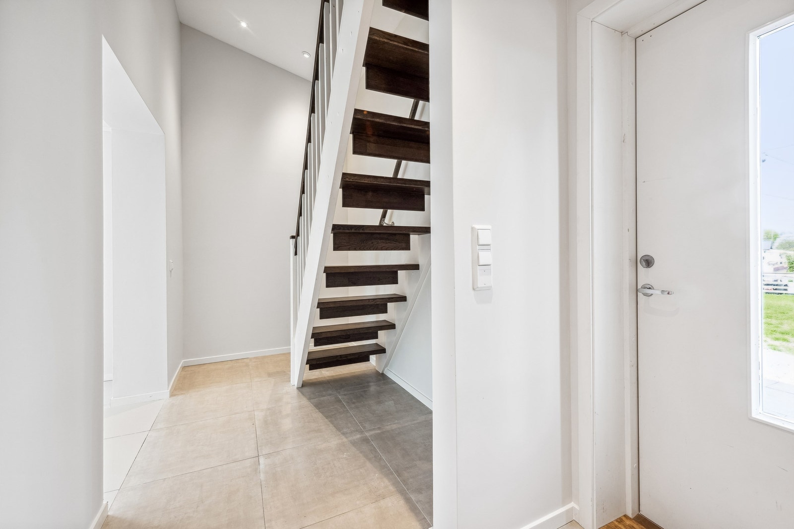 Entré, med flislagt gulv og slette, malte veggflater. Downlights. Galleribilde