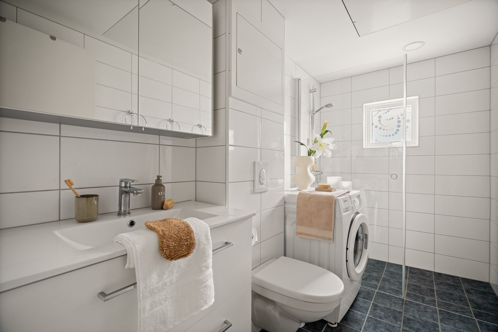 Lyst og helfliset bad med varmekabler i gulvet og opplegg for vaskemaskin Galleribilde