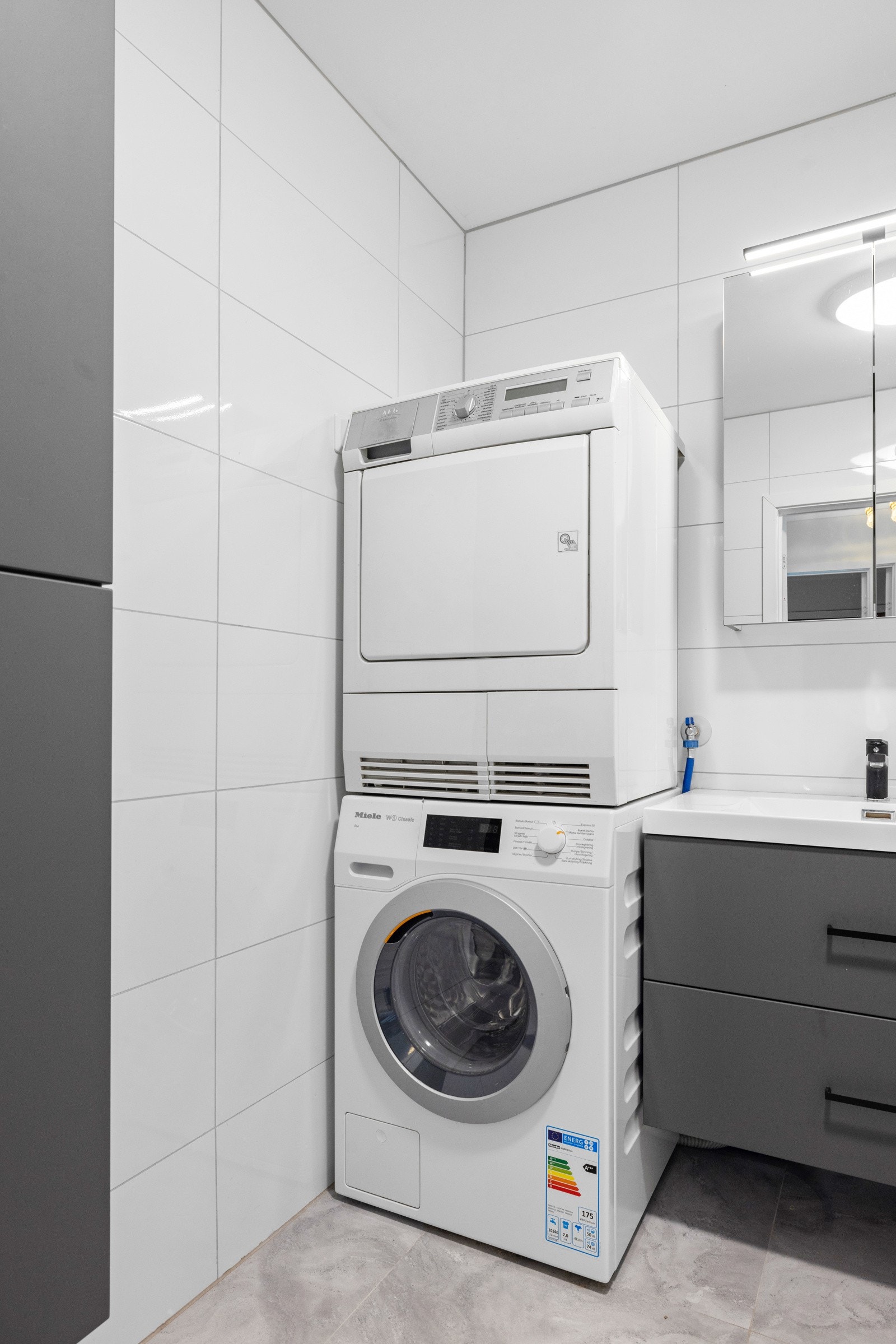 Innredningen på badet består av en heldekkende servant med mørke underskuffer, matchende høyskap og speilskap med lys Galleribilde