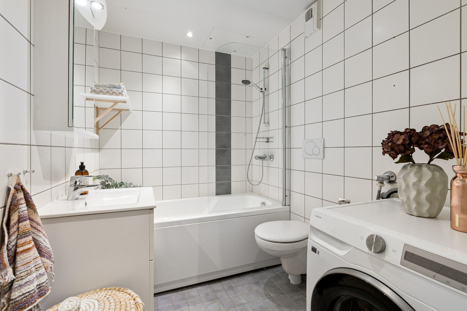 Badet har gulvfliser med varme og lyse veggfliser. Galleribilde