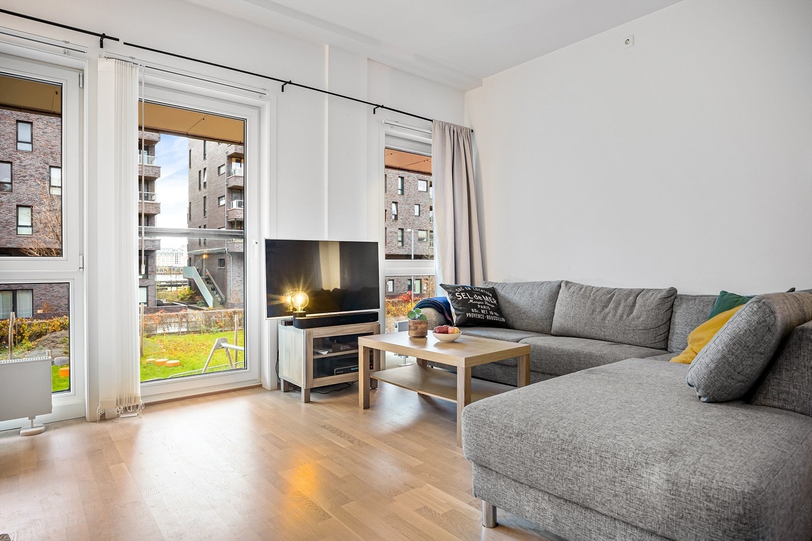 Lys stue med plass til sofagruppe, sofabord og underholdningsavdeling. Galleribilde