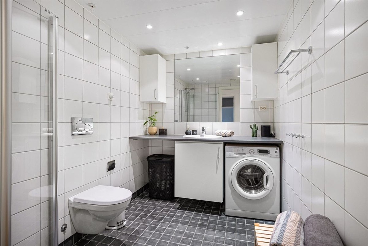 Lekkert baderom med vegghengt WC, dusjhjørne, servant over innredning, samt speil og vegghengte skap. Galleribilde