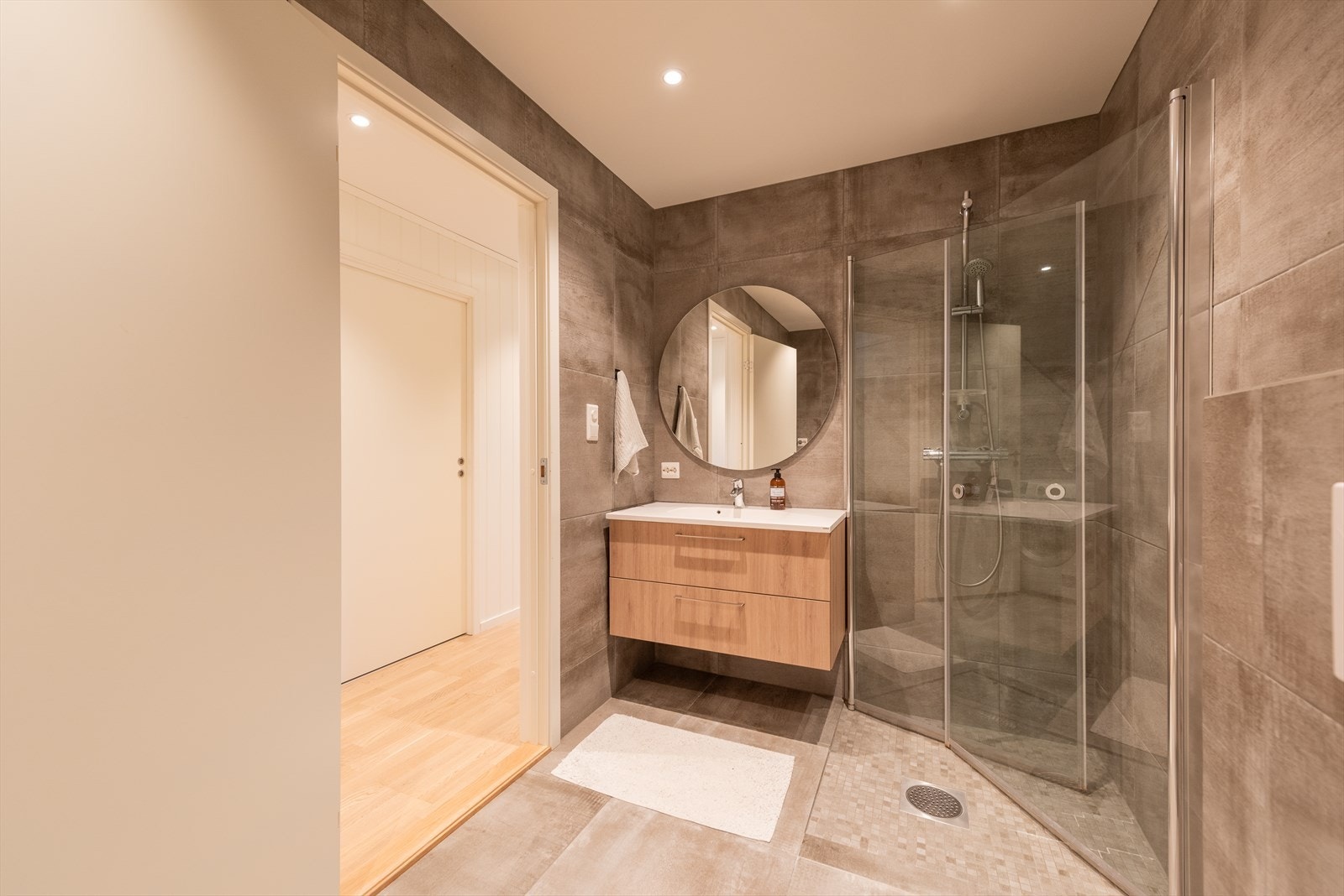 Badet i underetasjen har tilsvarende utførelse som det i etasjen over. Gulv og dusjsone er flislagt med store 60x60 fliser og det er innfelte downlights i himlingen. Galleribilde