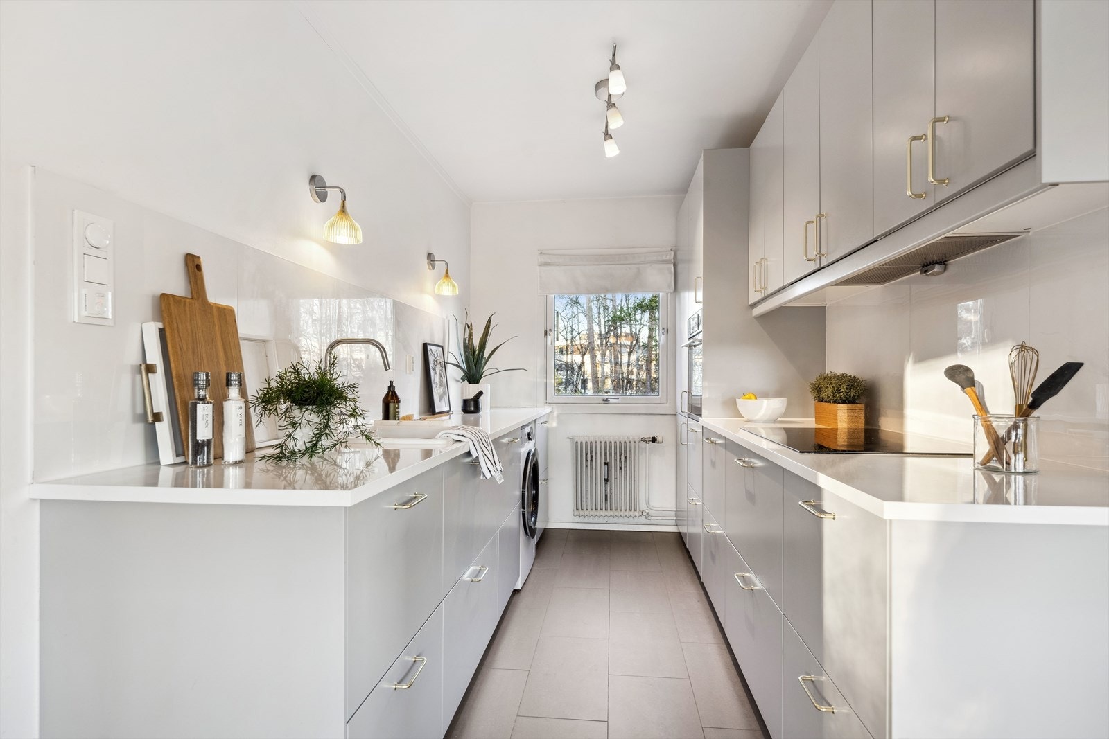 Kjøkken fra 2019 med en ryddig og moderne innredning med glatte flater og en benkeplate i kompositt med keramisk vask. Legg merke til flislagt gulv med varmekabler under. Galleribilde