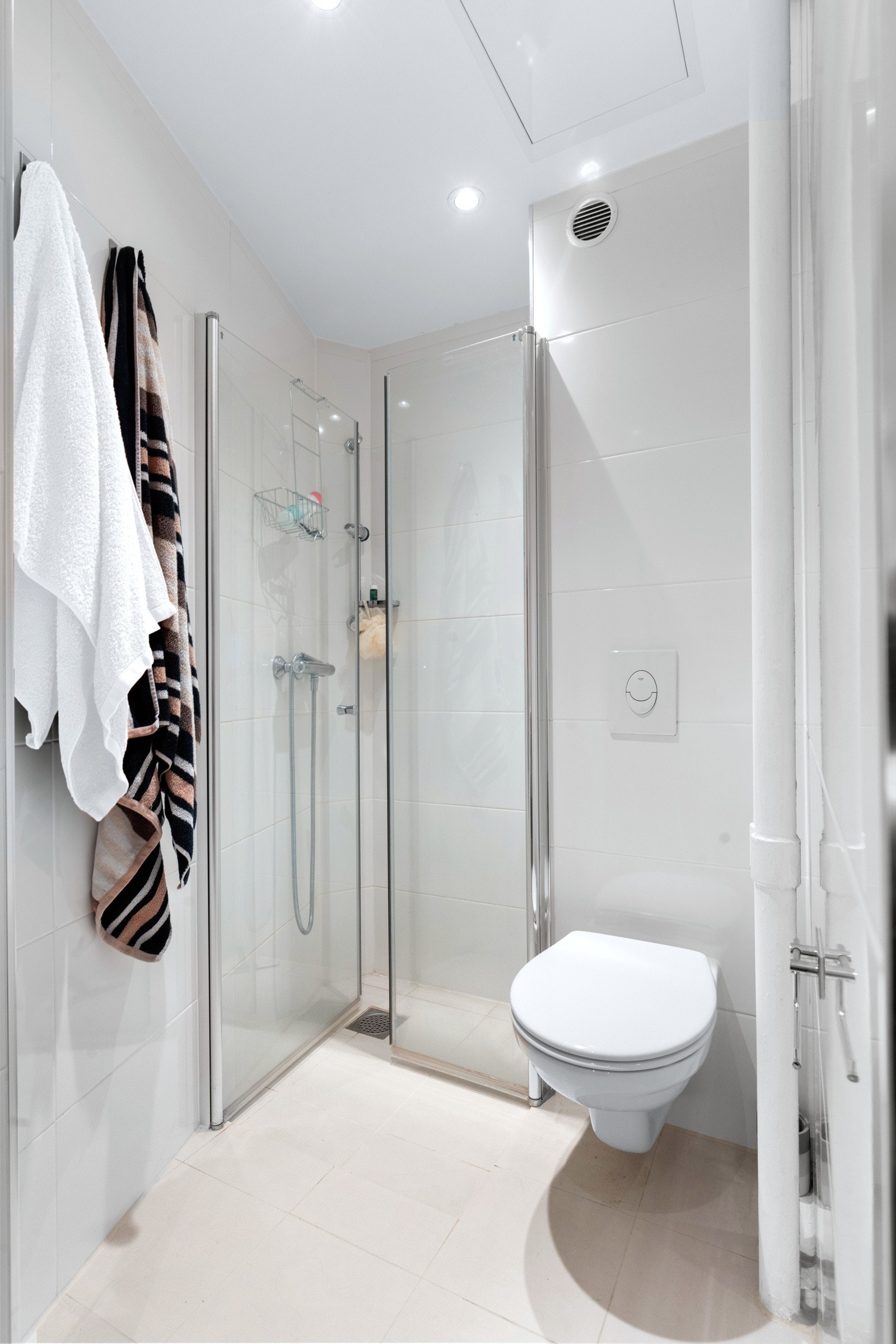 Delikat baderom fra 2020. Badet består av vegghengt toalett og dusjhjørne med to svingbare glassdører. Pen innredning med slette fronter og heldekkende servant Galleribilde