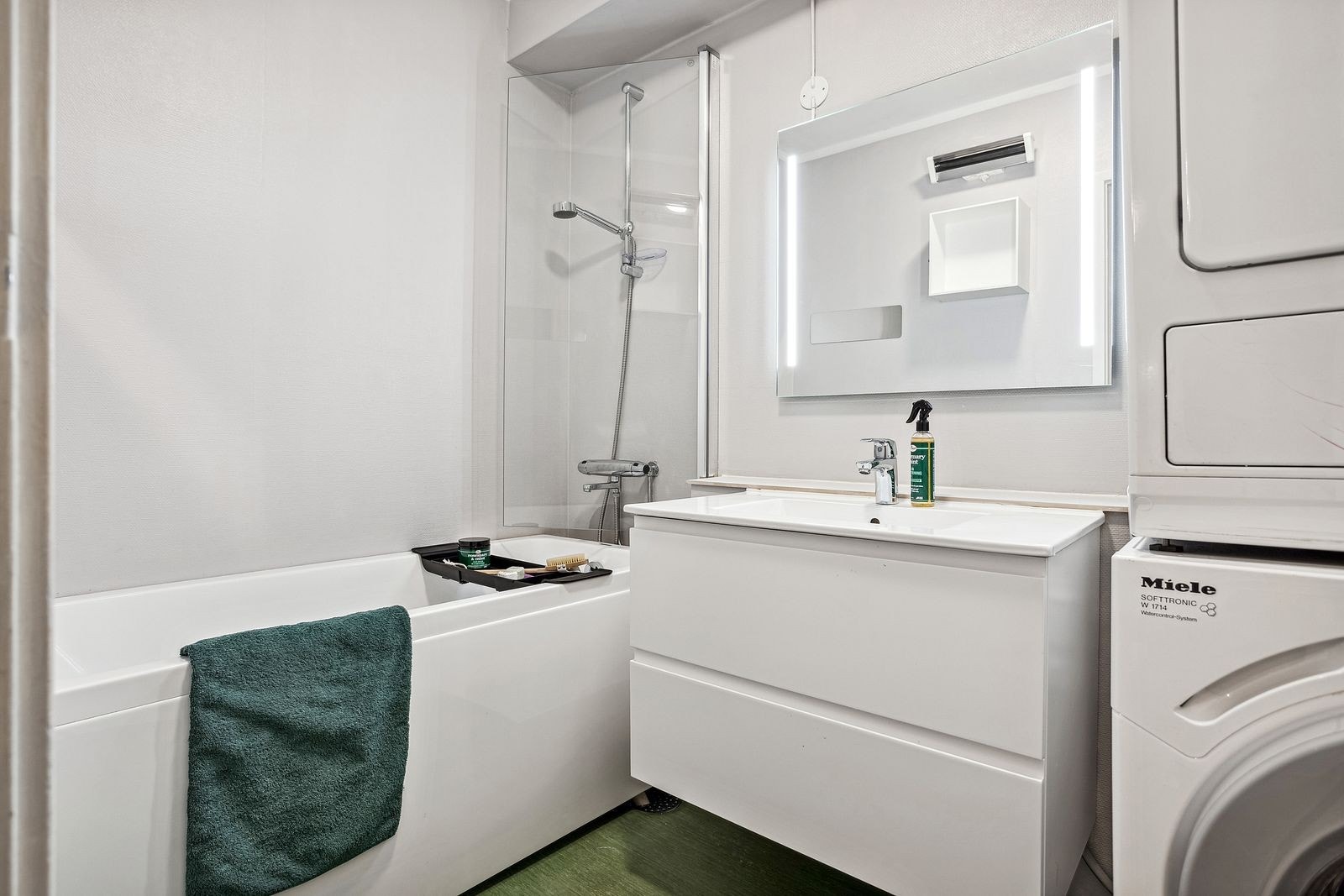 Badet er innredet med toalett, servant med to skuffer, badekar og dusj Galleribilde
