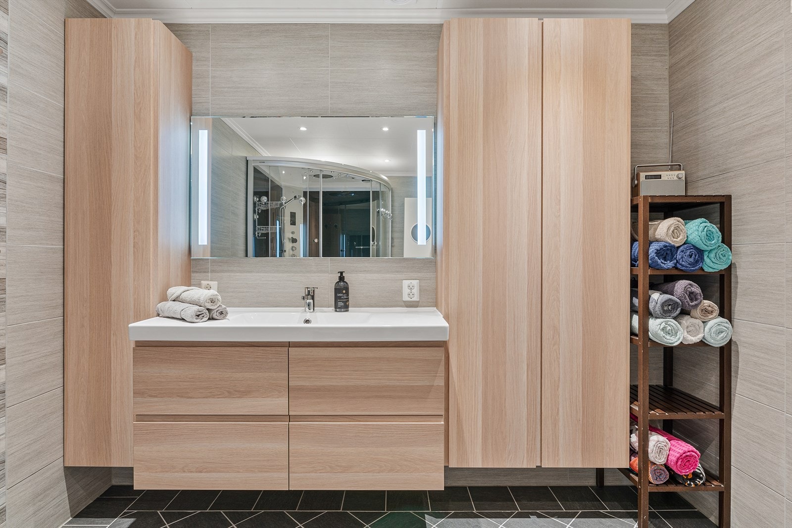 Rommet er praktisk innredet med vegghengt toalett, dusj/badekarkabinett og en stilren innredning med servant Galleribilde