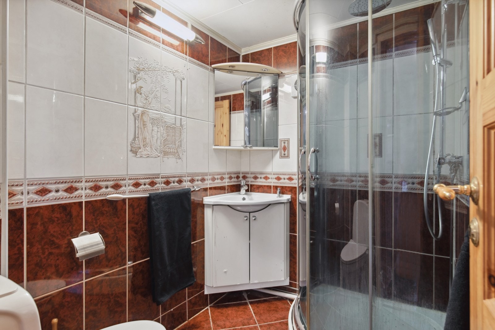 Gulvet er flislagt og har elektriske varmekabler. Rommet har innredet med servant, toalett, speil med lys og et dusjkabinett. Galleribilde