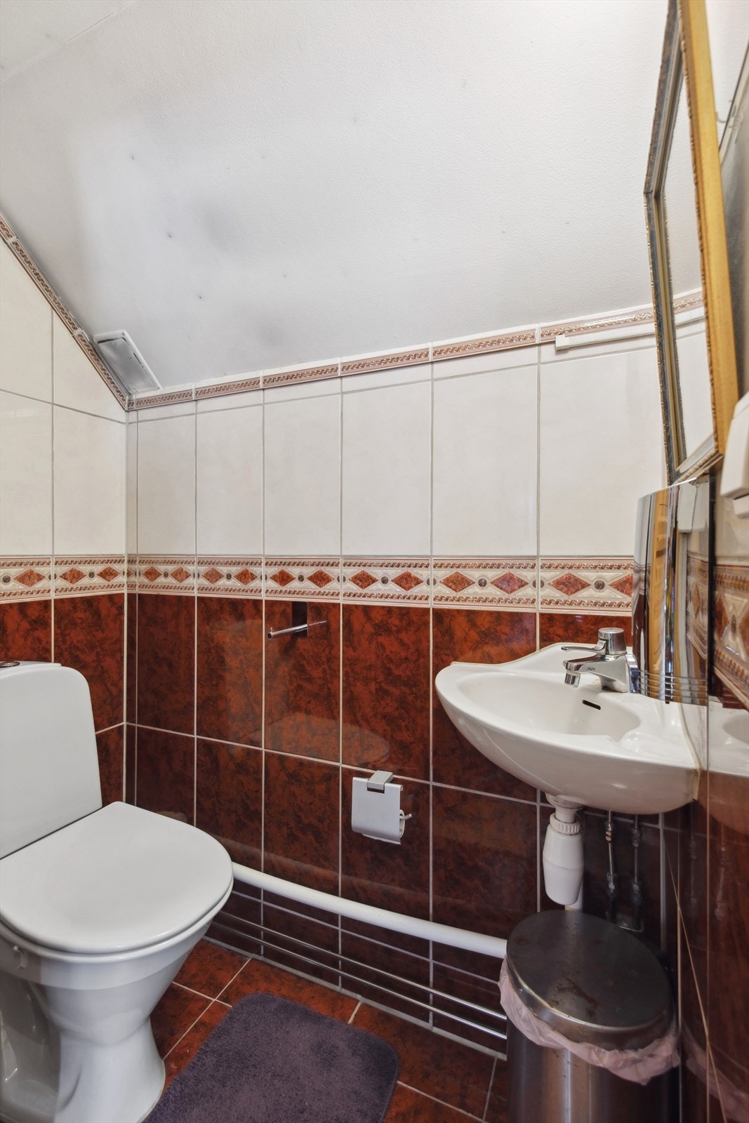 Et enkelt toalettrom med gulvmontert toalett og servant. Galleribilde